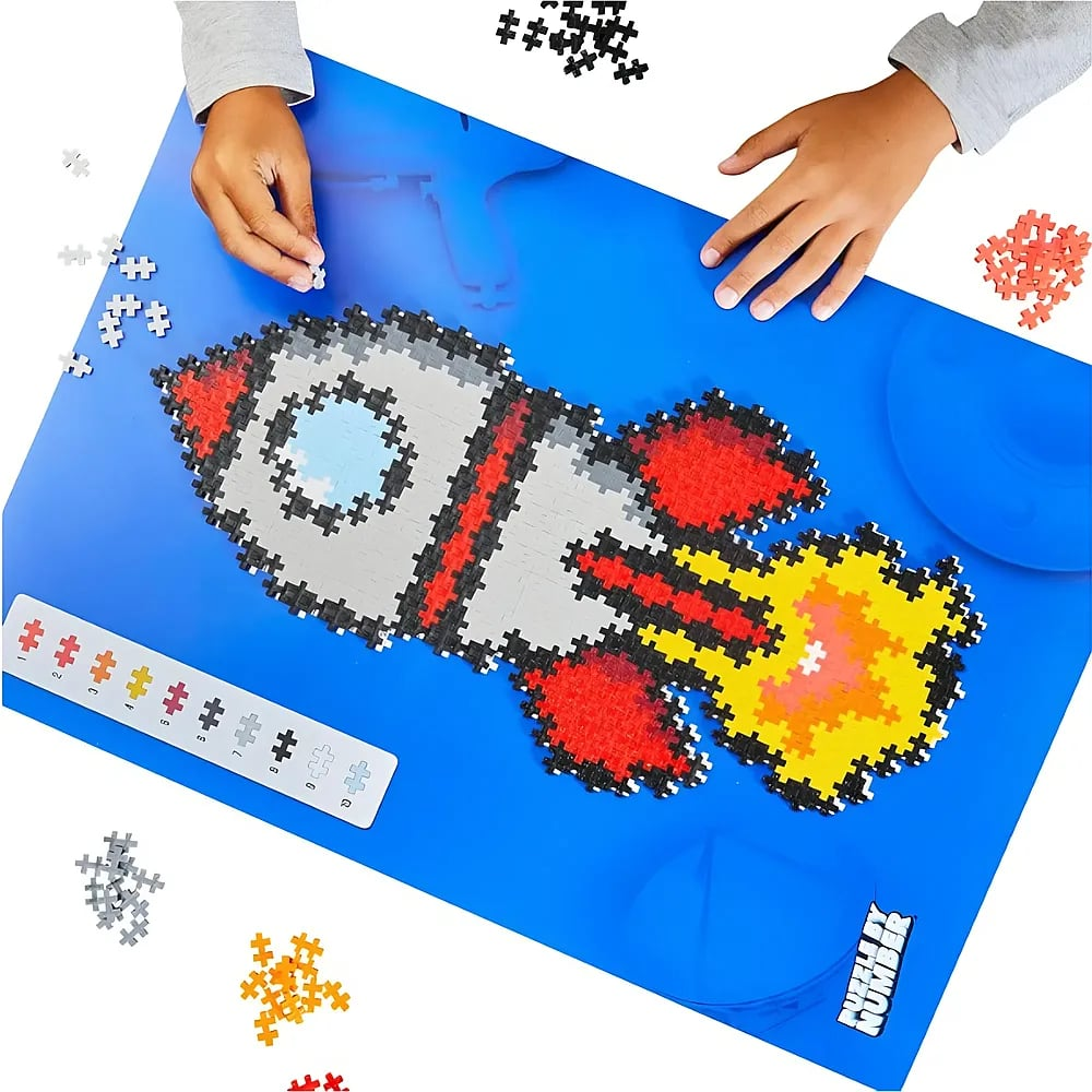 Un bambino costruisce un puzzle a razzo su un tappeto blu, unendo pezzi.
