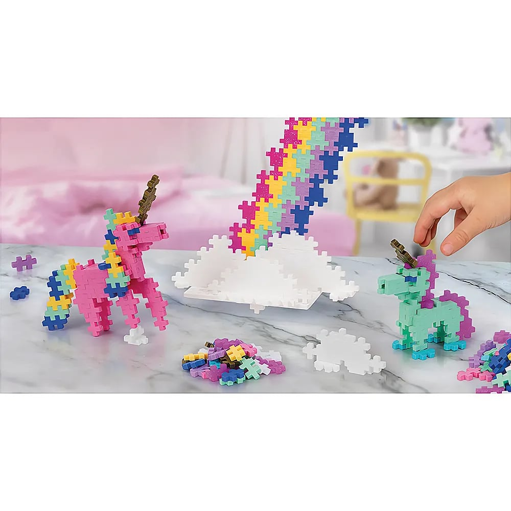 Bunte Einhorn-Figuren und ein Regenbogen aus Plus-Plus-Bausteinen auf einem Tisch.