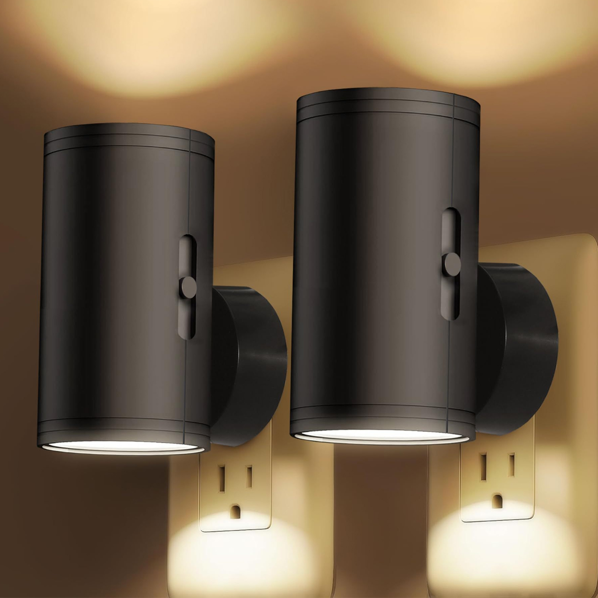 Zwei schwarze zylindrische LED-Nachtlichter stecken in Wandsteckdosen und strahlen warmes Licht aus.