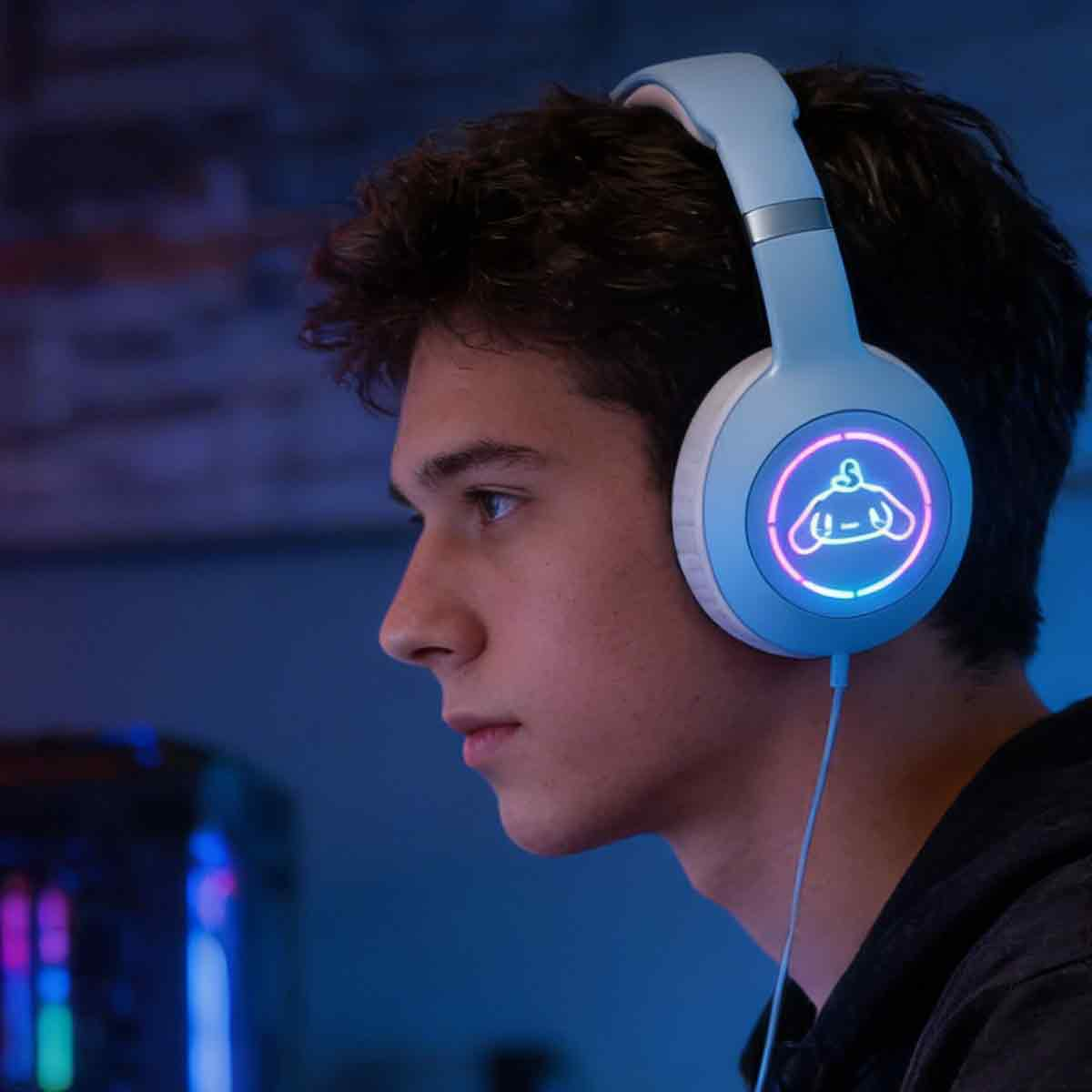Ein junger Mann trägt blaue Gaming-Kopfhörer mit beleuchtetem Logo in einem blau beleuchteten Raum.
