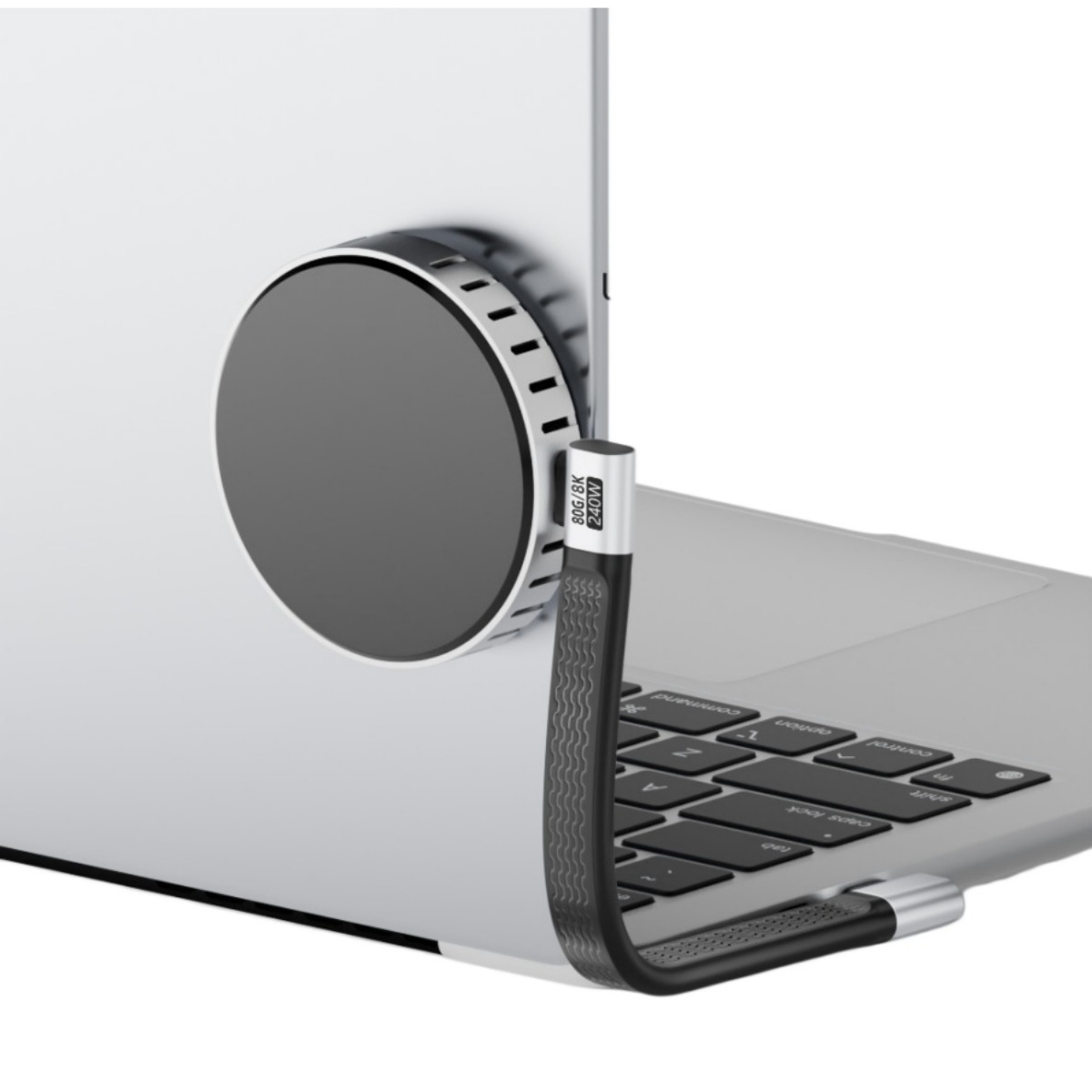 Ein runder Magnethub ist an der Seite des silbernen Laptops befestigt, mit einem gebogenen schwarzen Kabel.