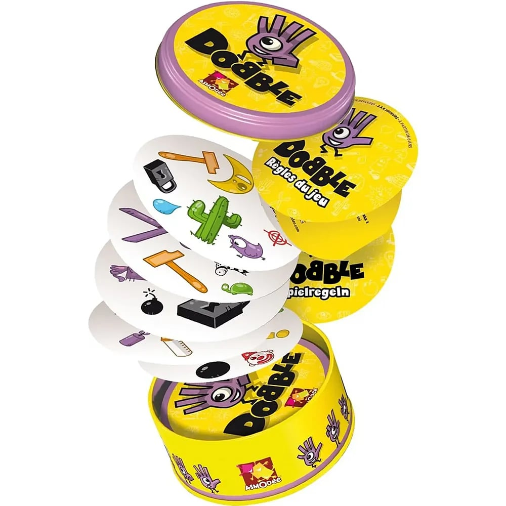 Le jeu de cartes Dobble sort d'une boîte jaune et violette, avec des cartes rondes et des symboles.
