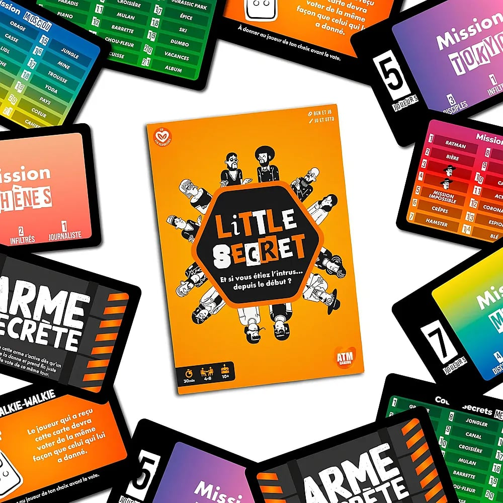 Das Brettspiel "Little Secret" liegt umgeben von mehreren bunten Spielkarten auf einem Tisch.