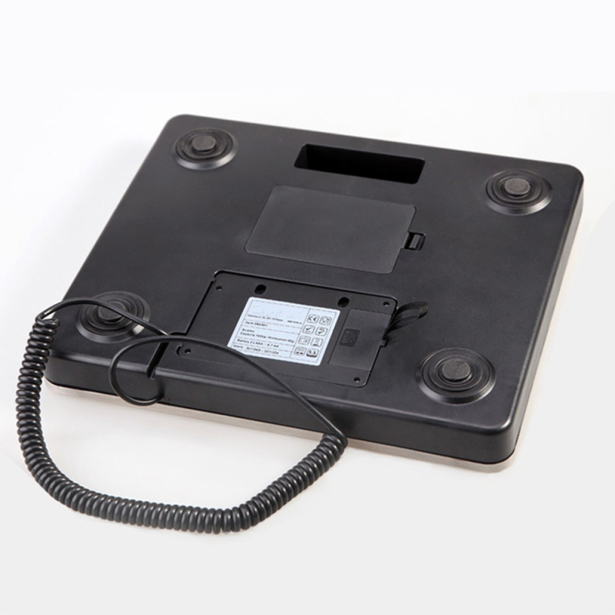 Die Unterseite einer schwarzen Digitalwaage mit vier runden Gummifüßen und einem gewickelten Kabel.
