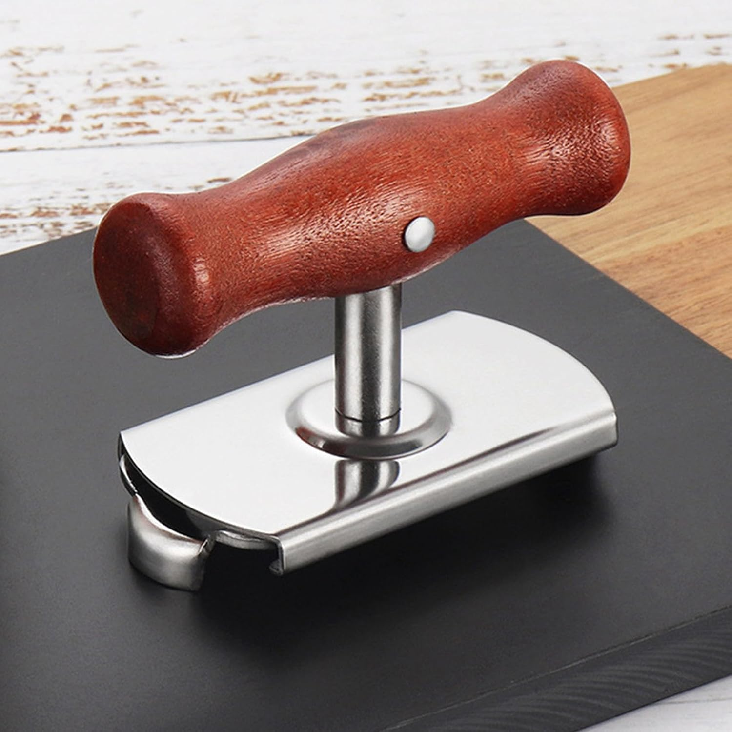Ein Dosenöffner mit braunem Holzgriff und silberner Metallbasis auf einer dunklen Platte.