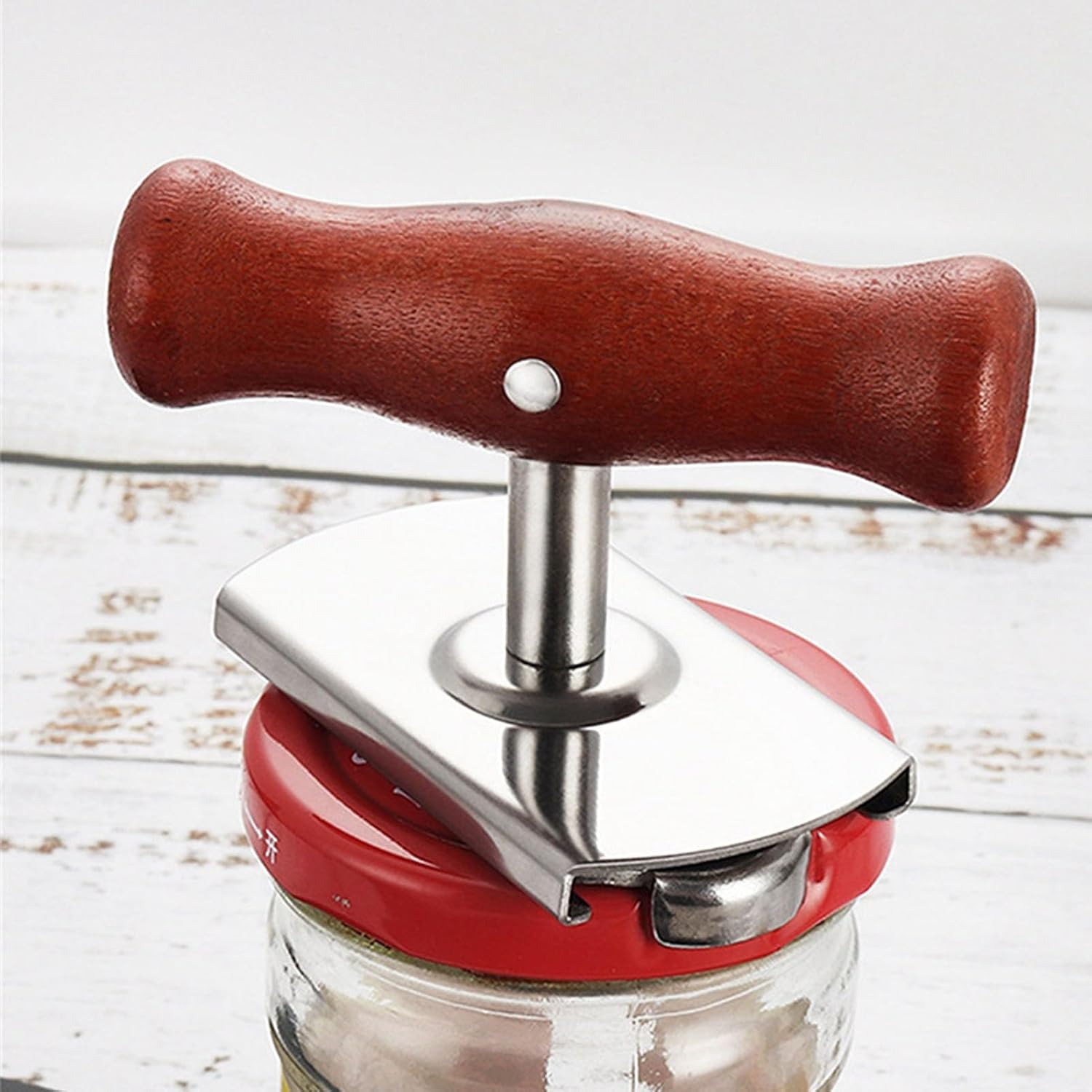 Ein Glas mit rotem Deckel und einem silbernen Deckelöffner mit Holzgriff.