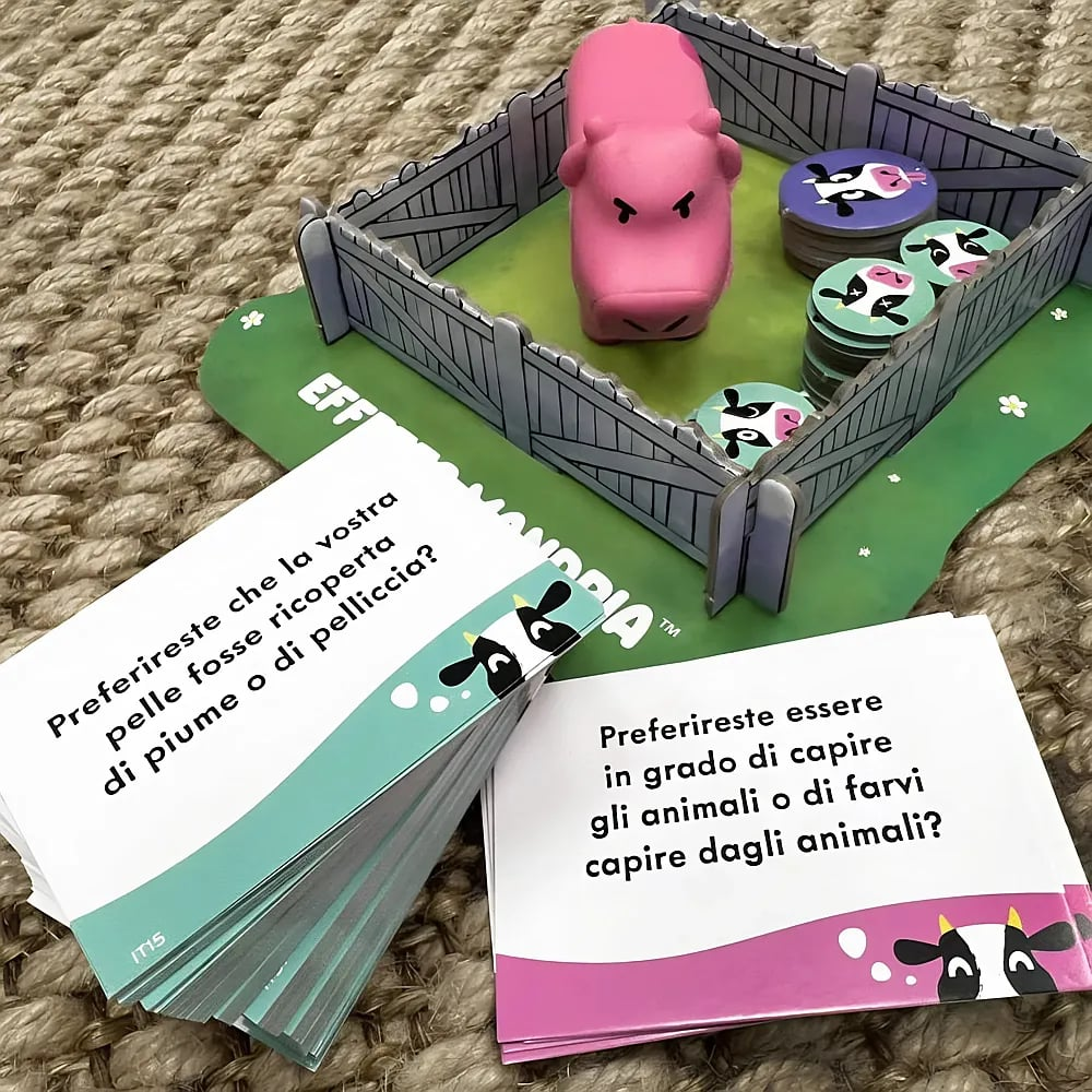 Un gioco da tavolo con un maialino rosa in un recinto, gettoni animali e carte di domande.