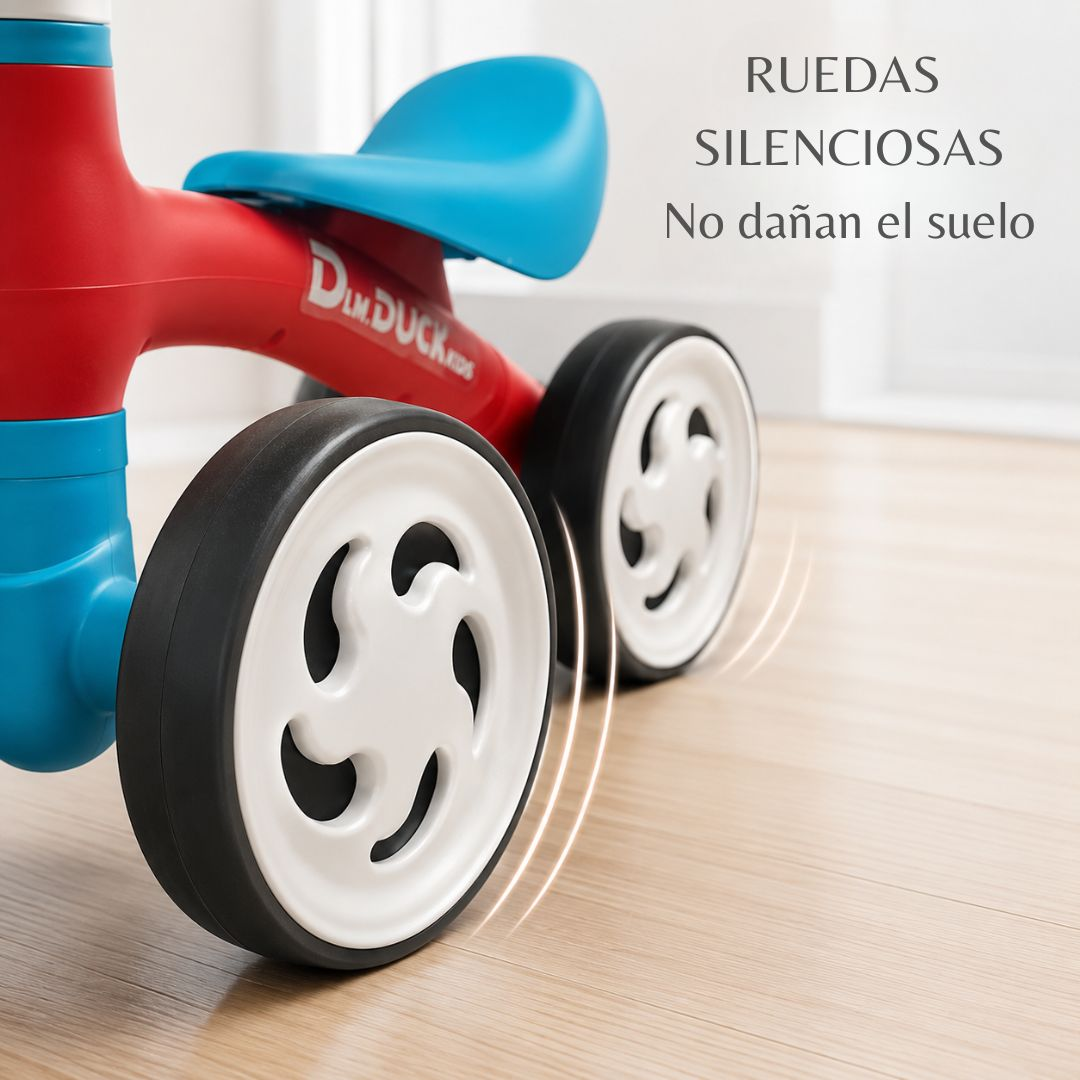 Triciclo infantil rojo y azul en suelo de madera con texto de ruedas silenciosas.