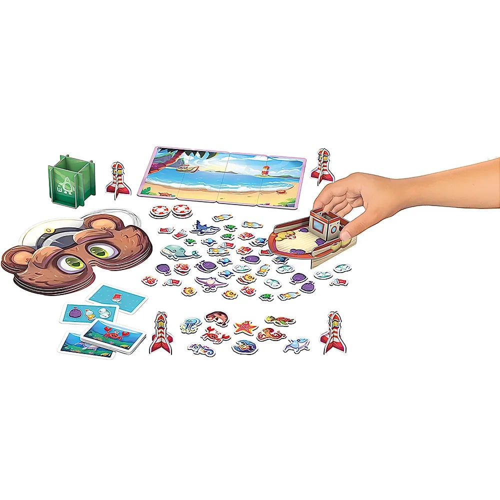 Eine Hand baut ein Kinderspiel mit bunten Meerestieren, Karten und einer Strandkulisse auf.