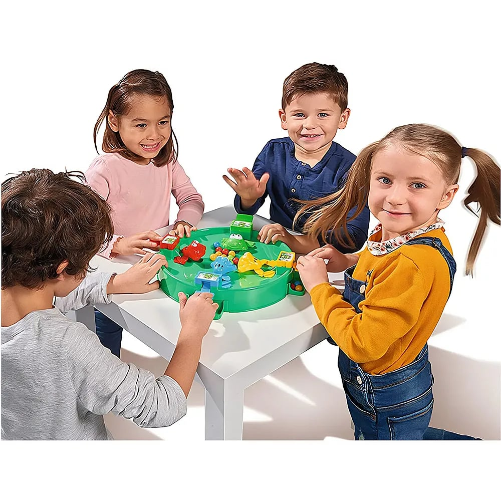 Quatre enfants jouent joyeusement à un jeu de grenouilles vertes sur une table blanche.