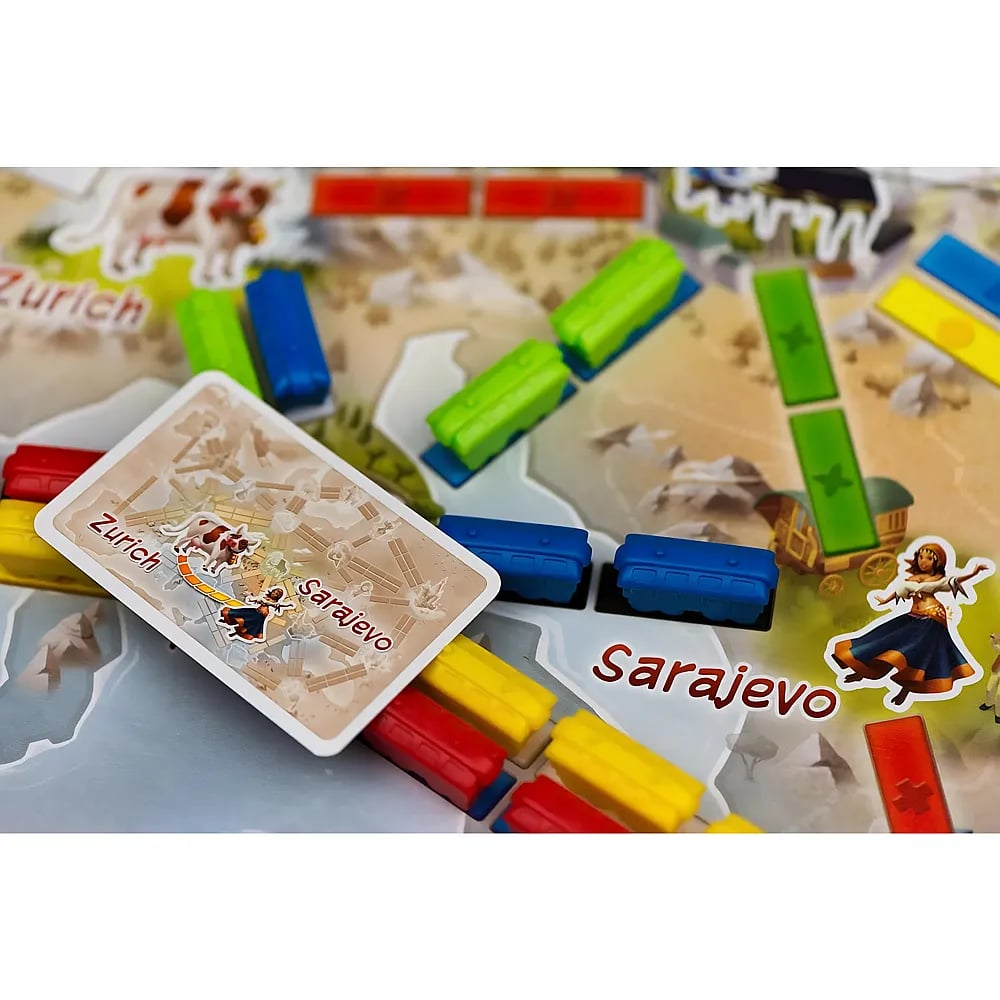 Ein Brettspiel zeigt farbige Zugfiguren und eine Zielkarte mit der Aufschrift Zürich nach Sarajevo.