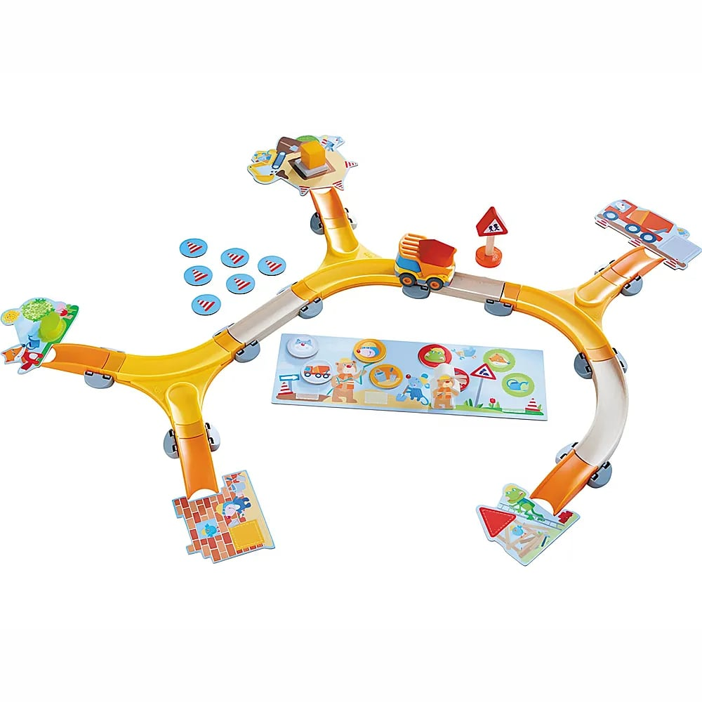 Una pista giocattolo colorata con rampe gialle, gettoni blu, un camioncino giocattolo e tabelloni illustrati su pavimento bianco.