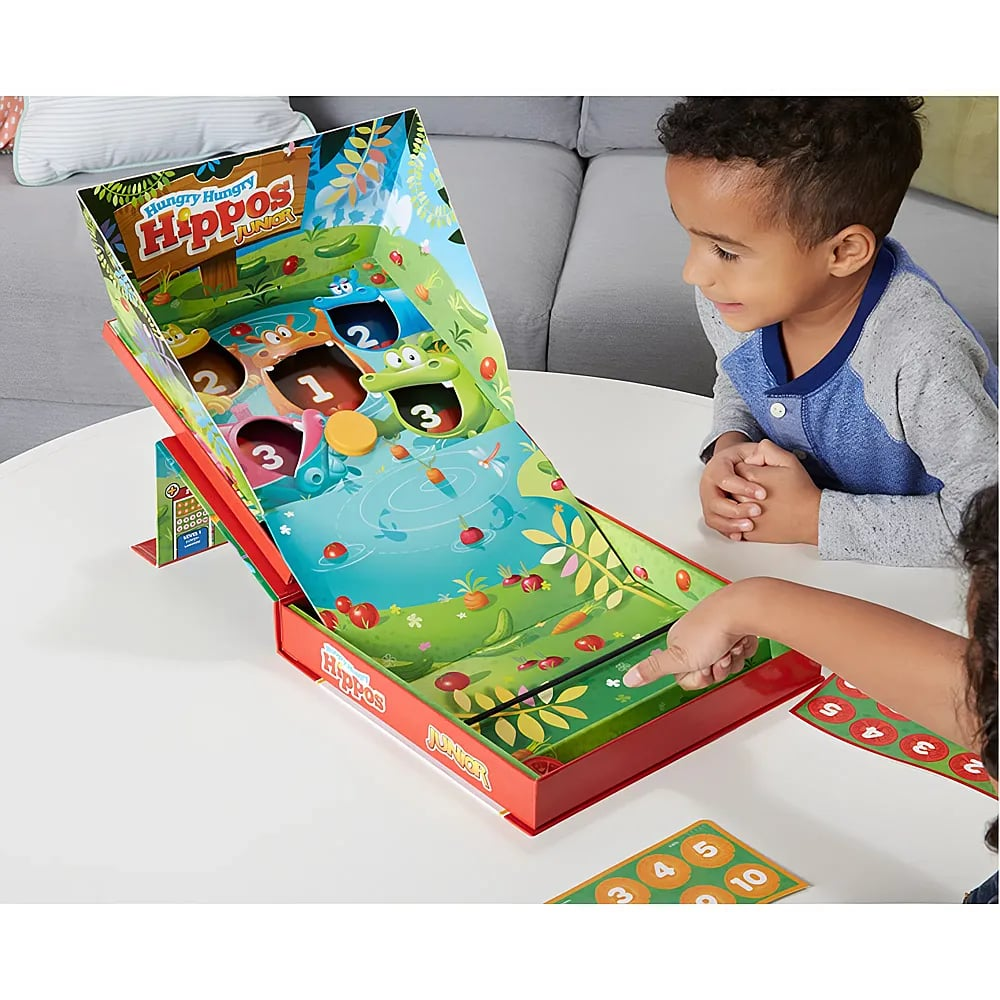 Due bambini giocano a Hungry Hungry Hippos Junior su un tavolo con una rampa colorata.