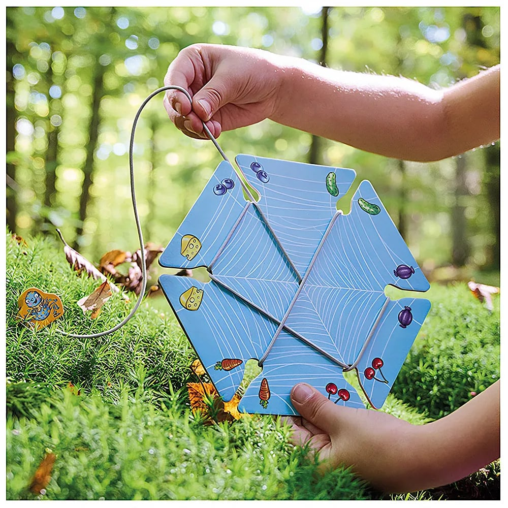 Ein Kind hält eine blaue Puzzlestruktur mit einer Schnur im Wald.