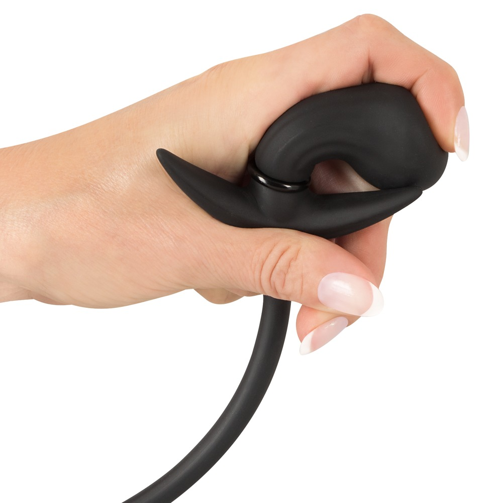 Eine Hand hält ein schwarzes, skulpturales Wellness-Accessoire mit glatter Oberfläche vor weißem Hintergrund.