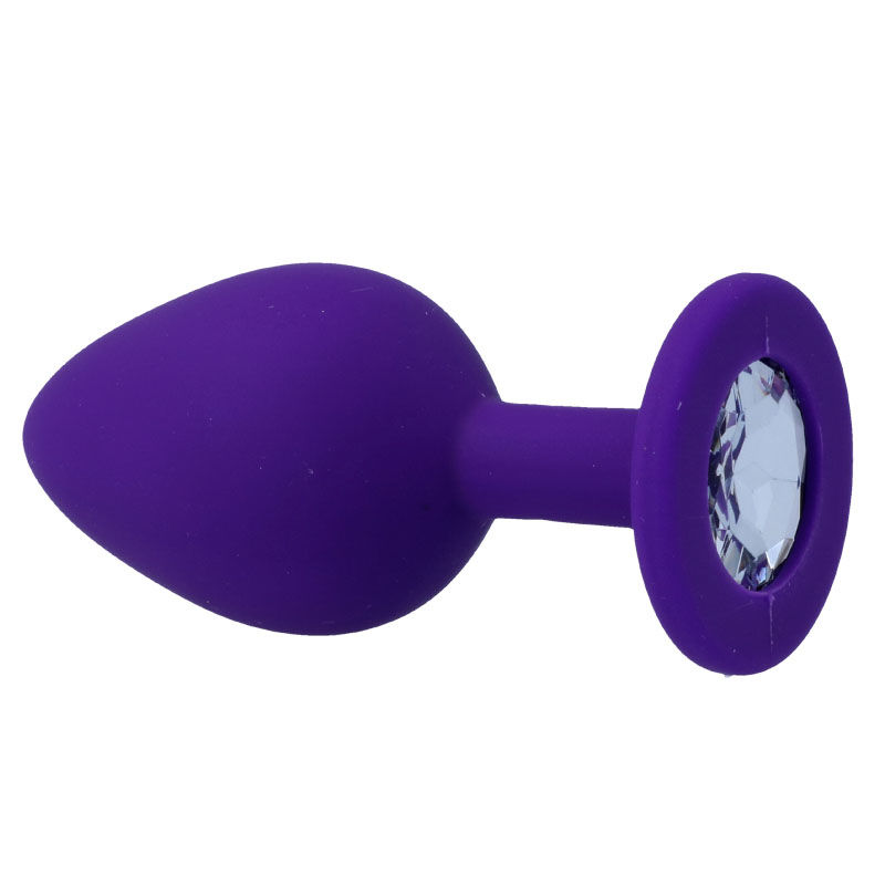 Ein lilafarbener Butt-Plug aus Silikon mit einem facettierten Schmuckstein im breiten Sockel vor weißem Hintergrund.