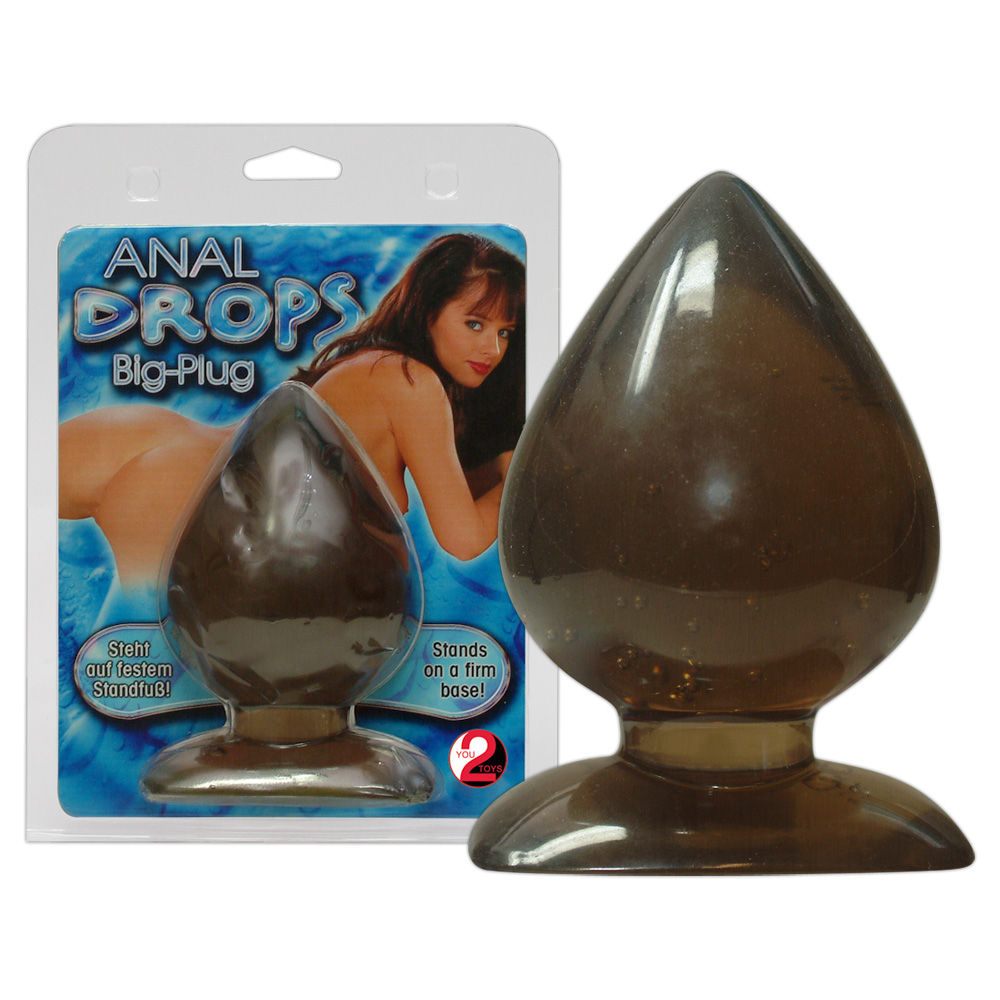 Ein tropfenförmiger, dunkel durchlässiger Plug mit flachem Fuß, neben der Produktverpackung.