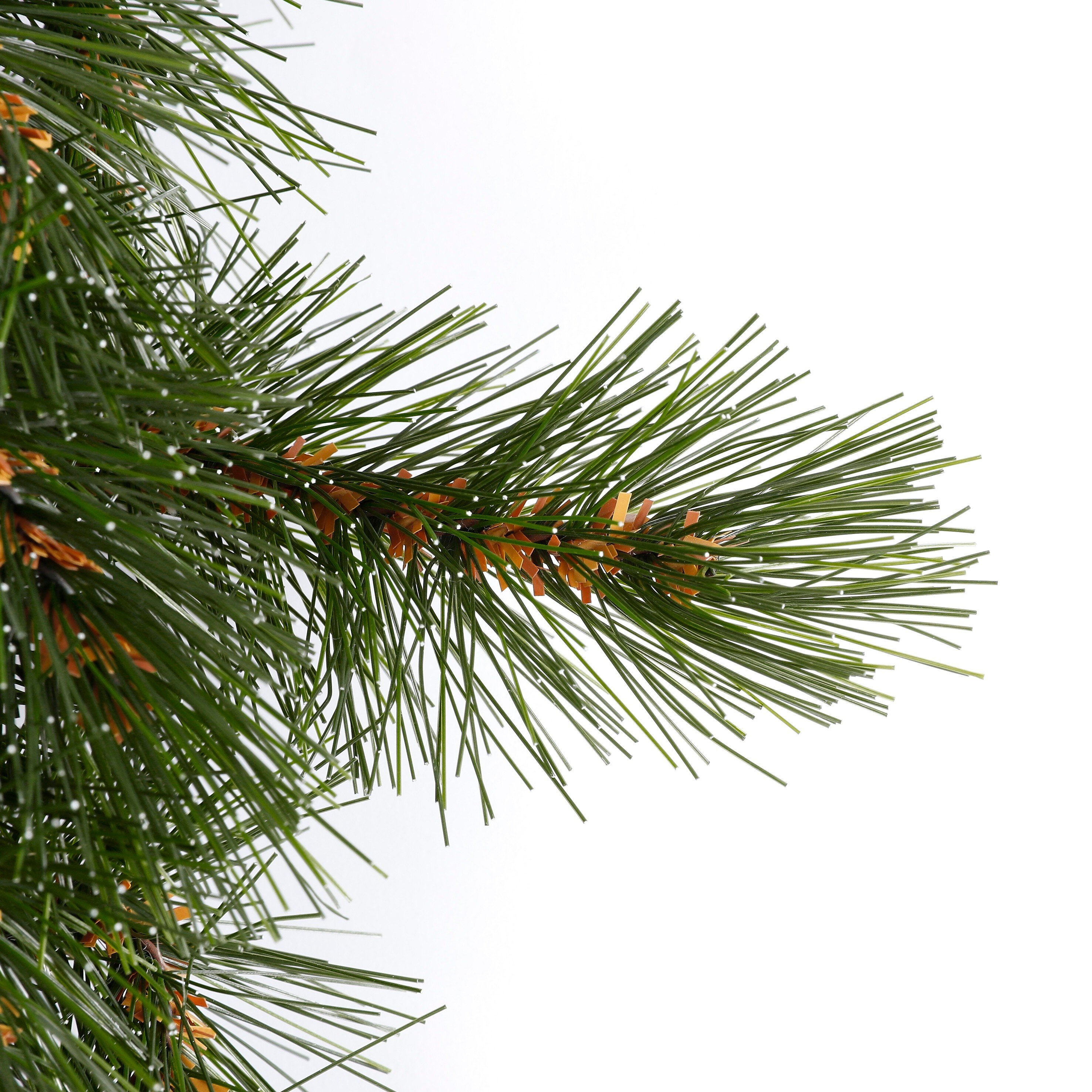 Green artificial pine branches with white snow spots on a bright background.