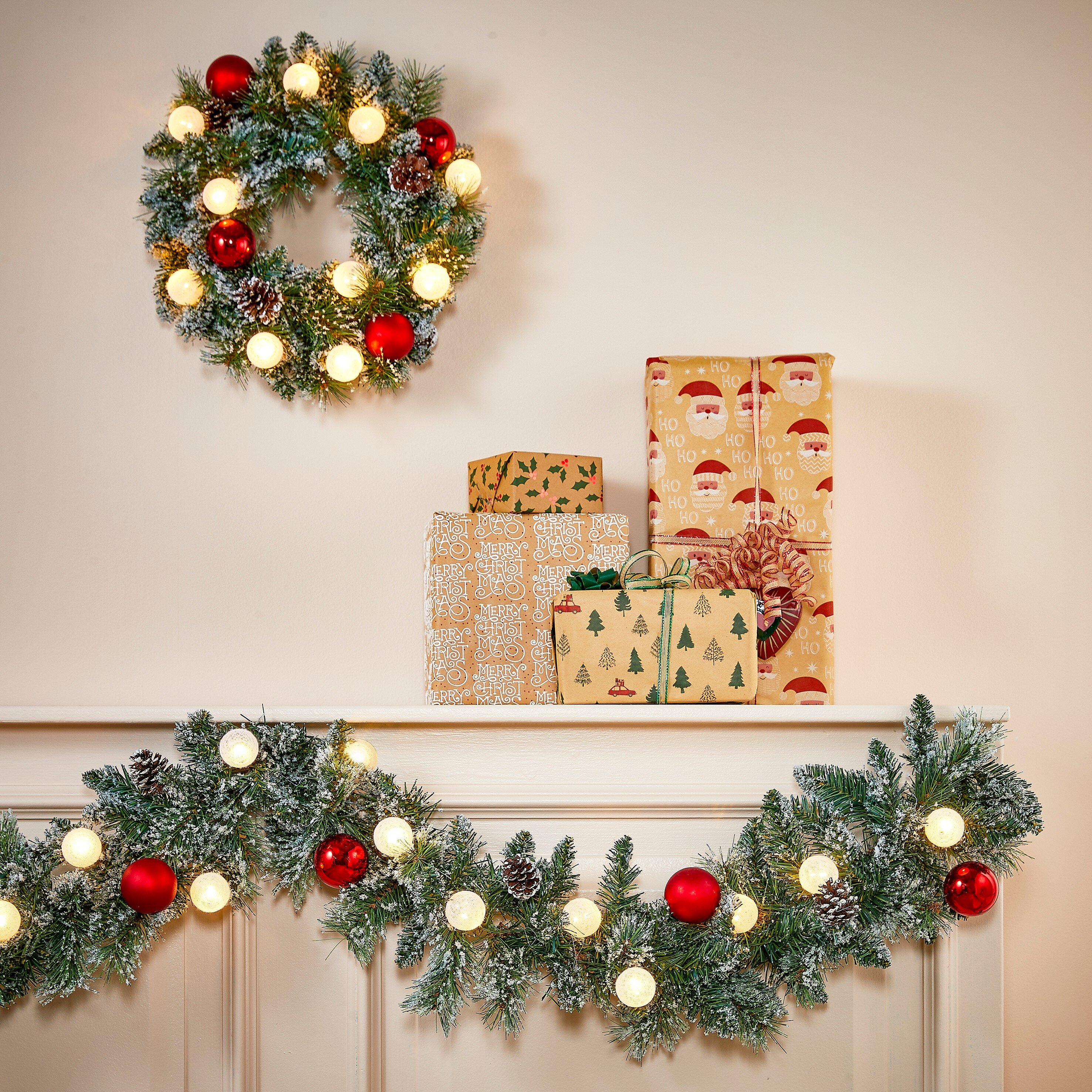 Ein geschmückter Kaminsims mit Geschenken, beleuchteter Girlande und einem passenden Weihnachtskranz.