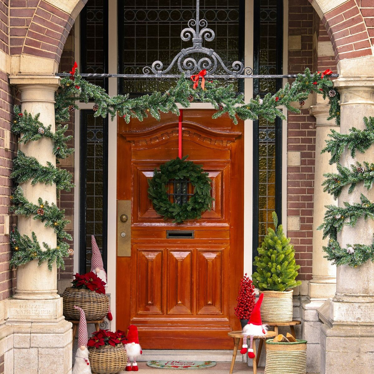 Une belle porte de Noël décorée de guirlandes, d'une couronne, de nains et de verdure festive.