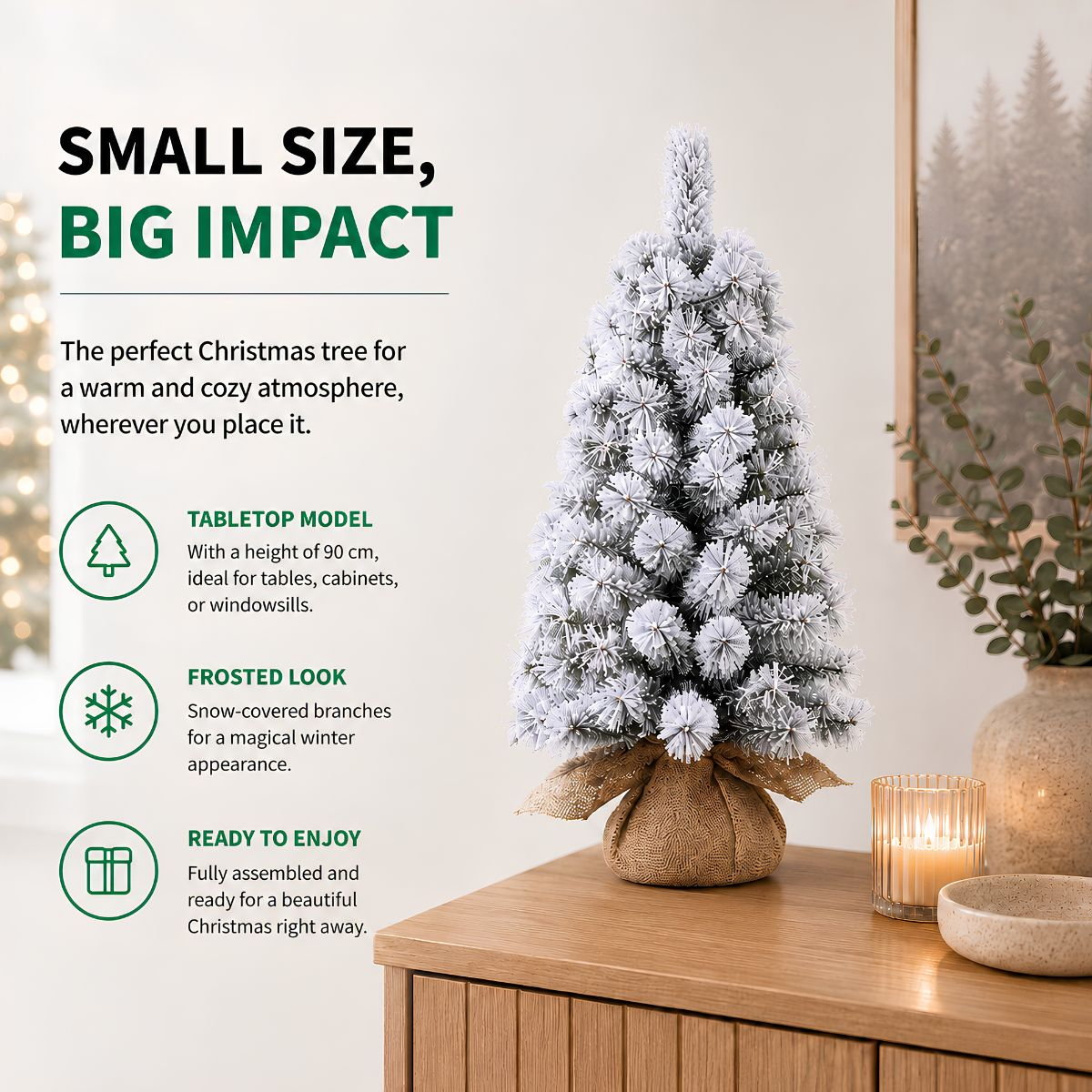 Small frosted artificial Christmas tree on a wooden table with a candle and text.
