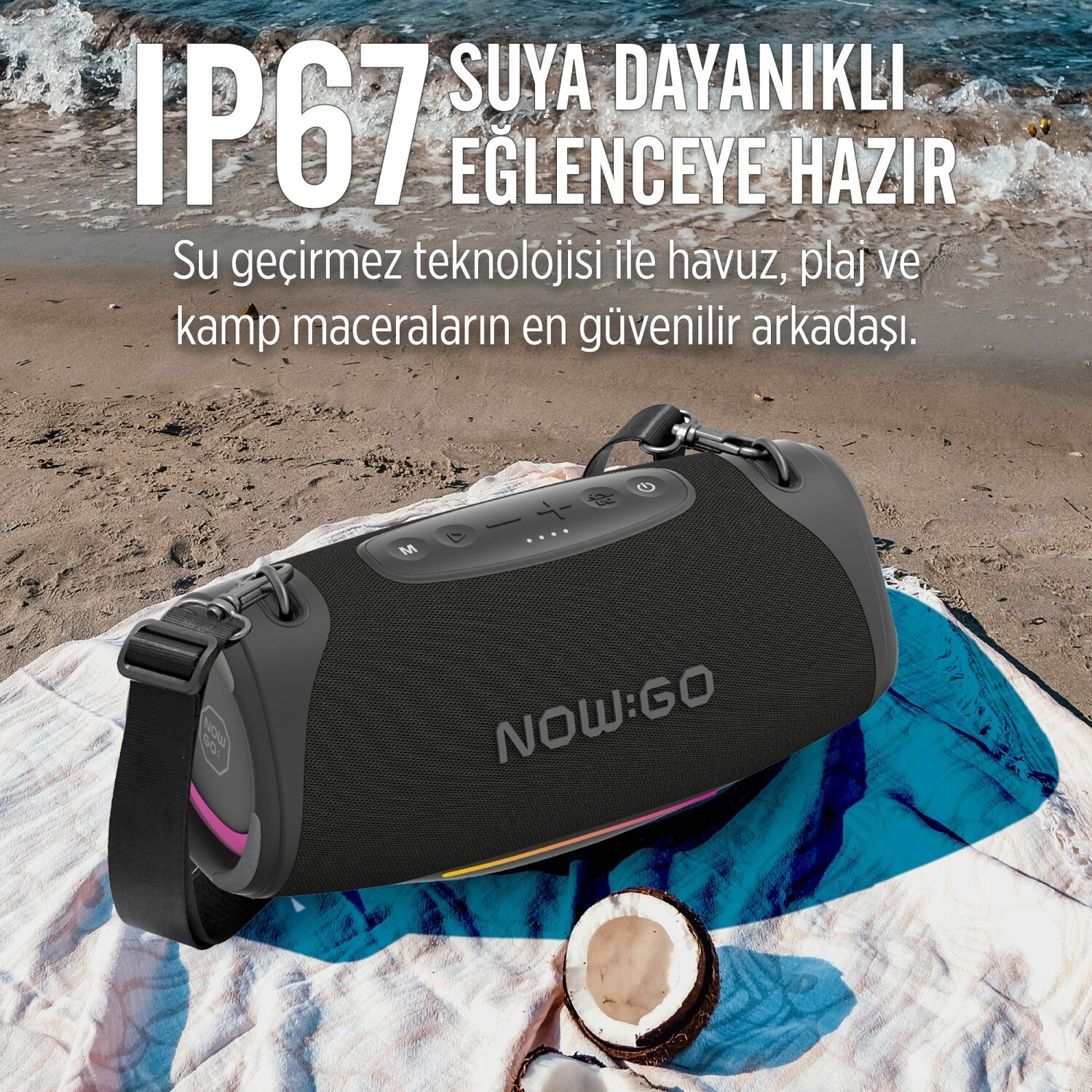 Czarny głośnik Bluetooth NOW:GO na ręczniku plażowym na piasku.