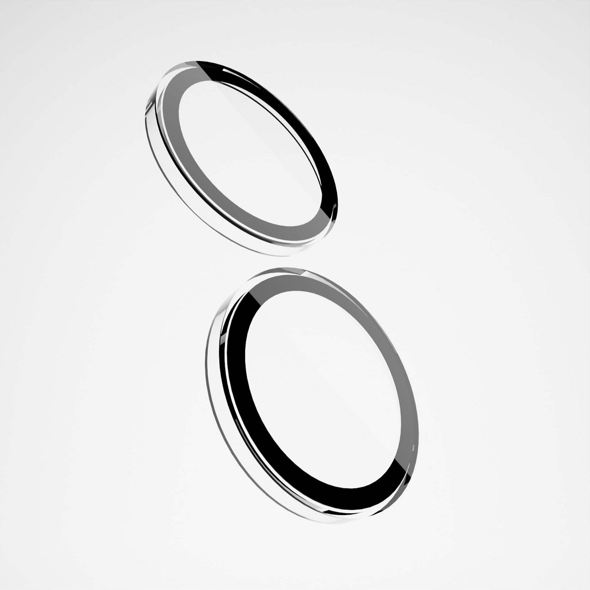 Dos objetos de anillos circulares brillantes en blanco y negro flotando sobre un fondo blanco liso.