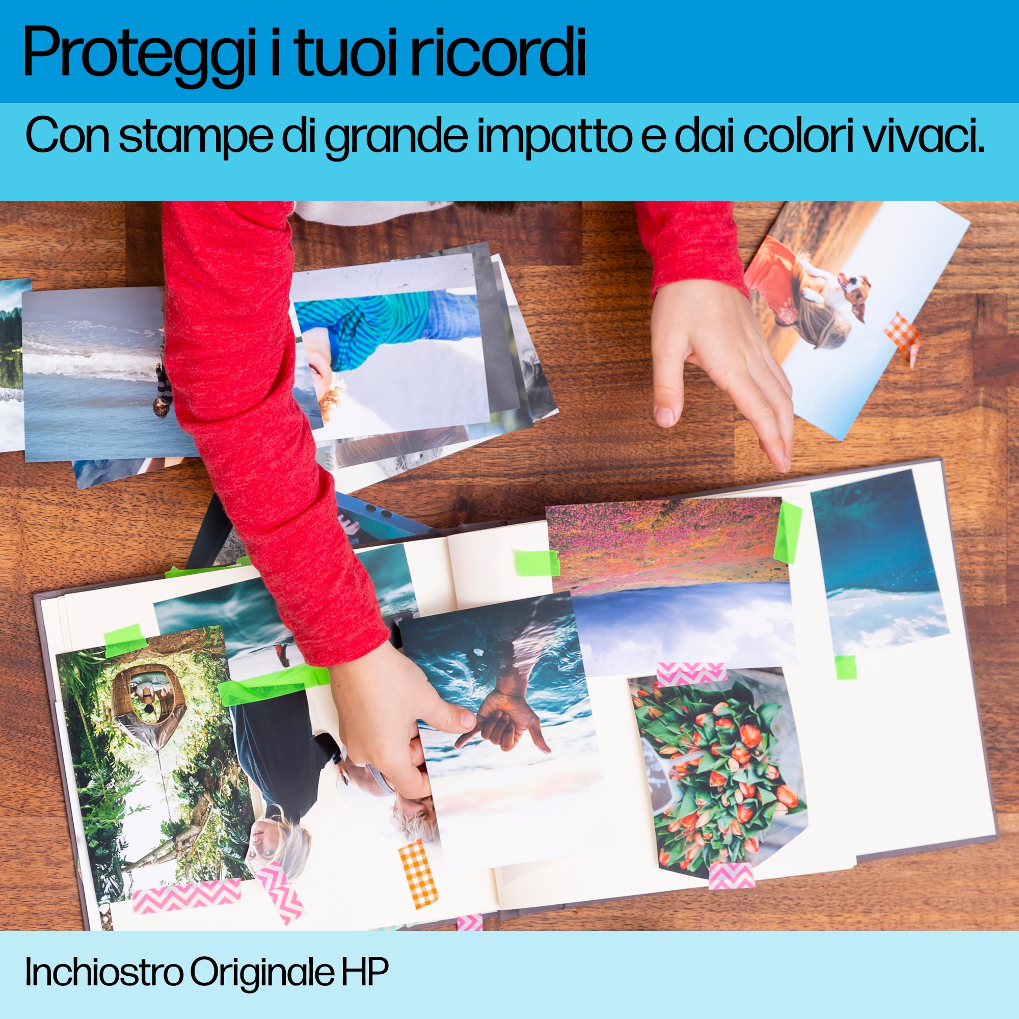 A child in a red sweater arranges colorful photos in a photo album on a wooden table.
