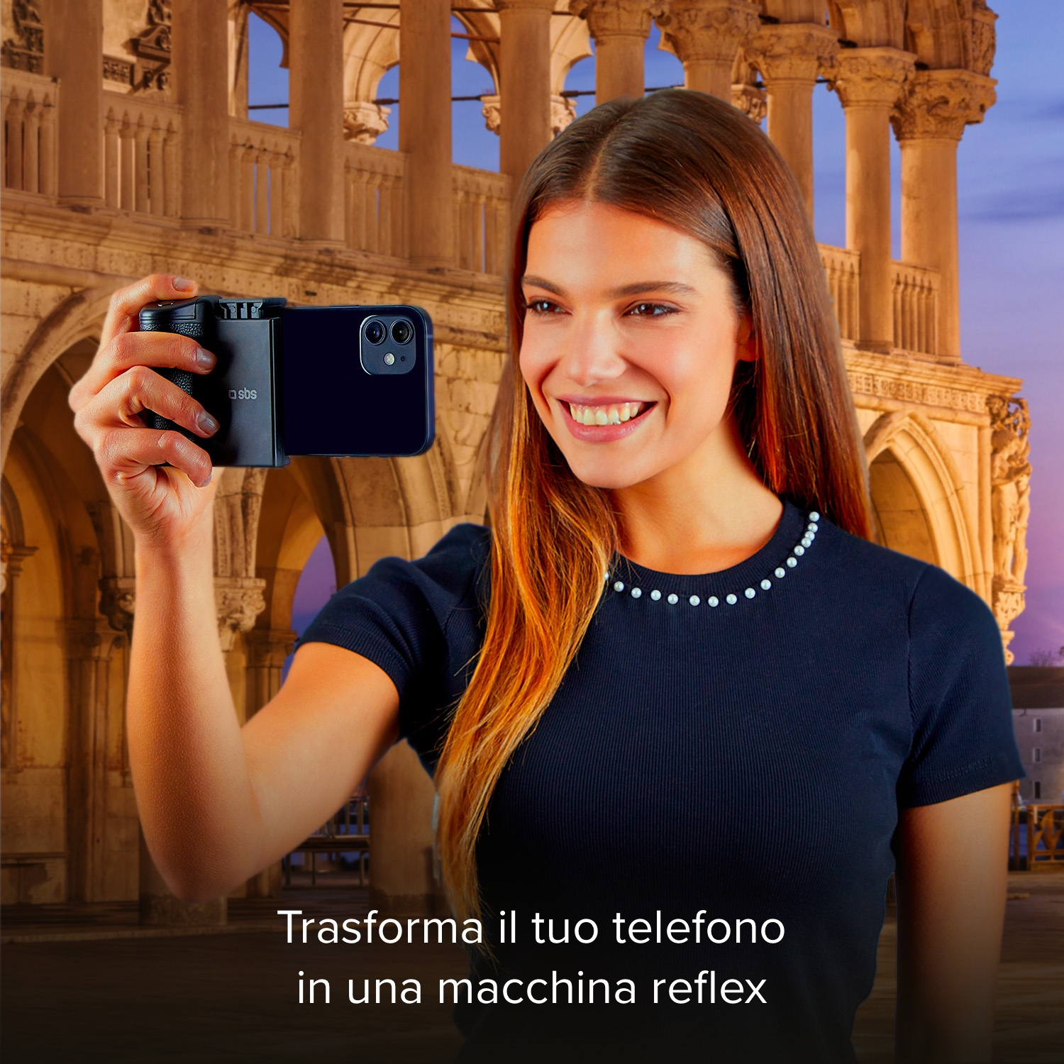 Una mujer sonriente sostiene un smartphone con empuñadura de cámara ante un edificio histórico.