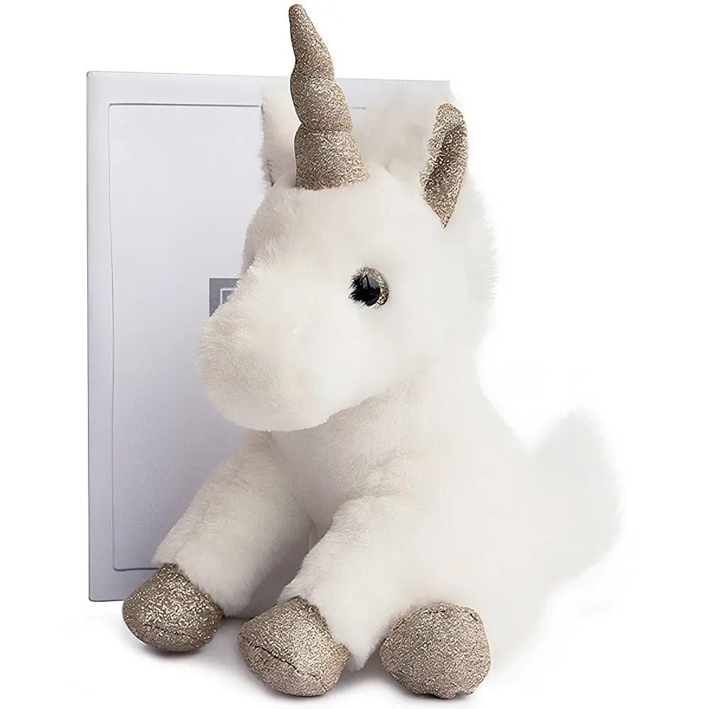 Un unicorno di peluche bianco con zoccoli, orecchie e corno dorati scintillanti siede davanti a una scatola bianca.