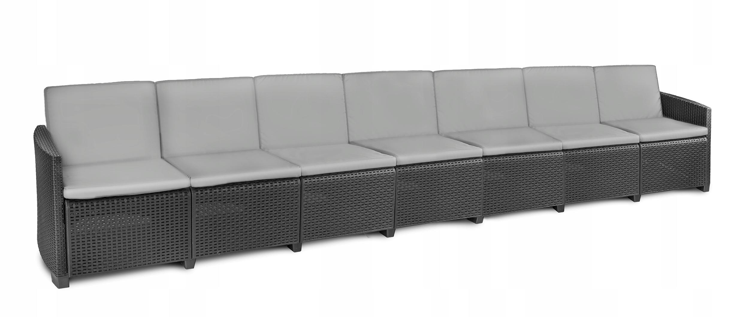 Długa ciemnobrązowa sofa wiklinowa z jasnoszarymi poduszkami na białym tle.