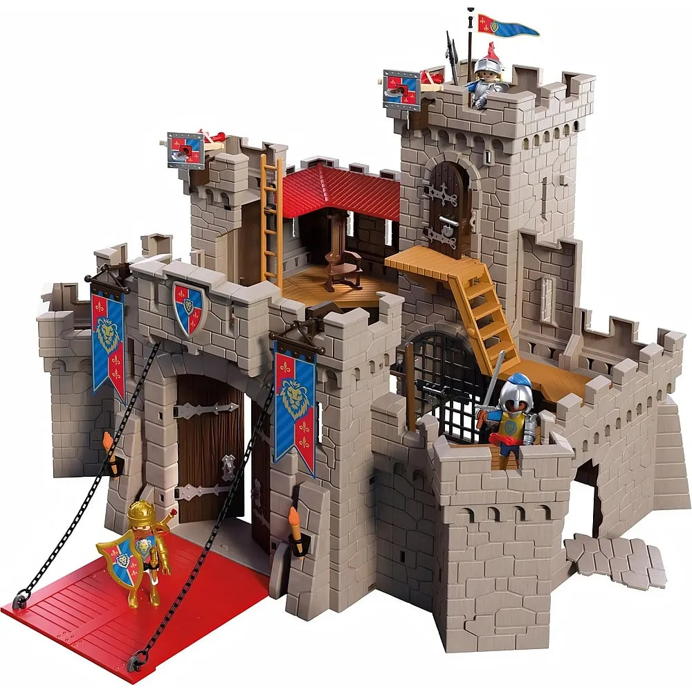 Un castillo de juguete de plástico con figuras, murallas, torres y un puente levadizo rojo sobre fondo blanco.