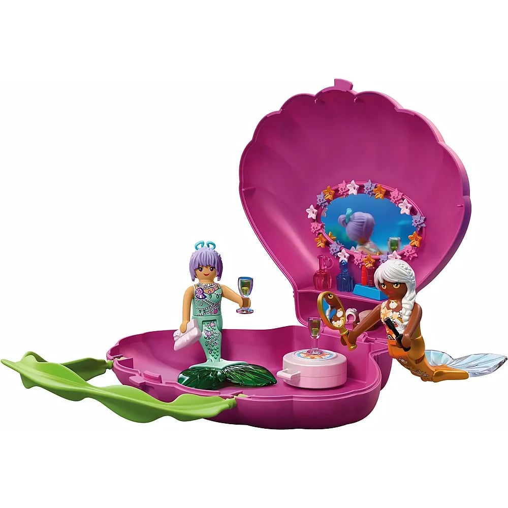 Dos sirenas de juguete dentro de una concha rosa abierta con espejo, botellas pequeñas y accesorios.