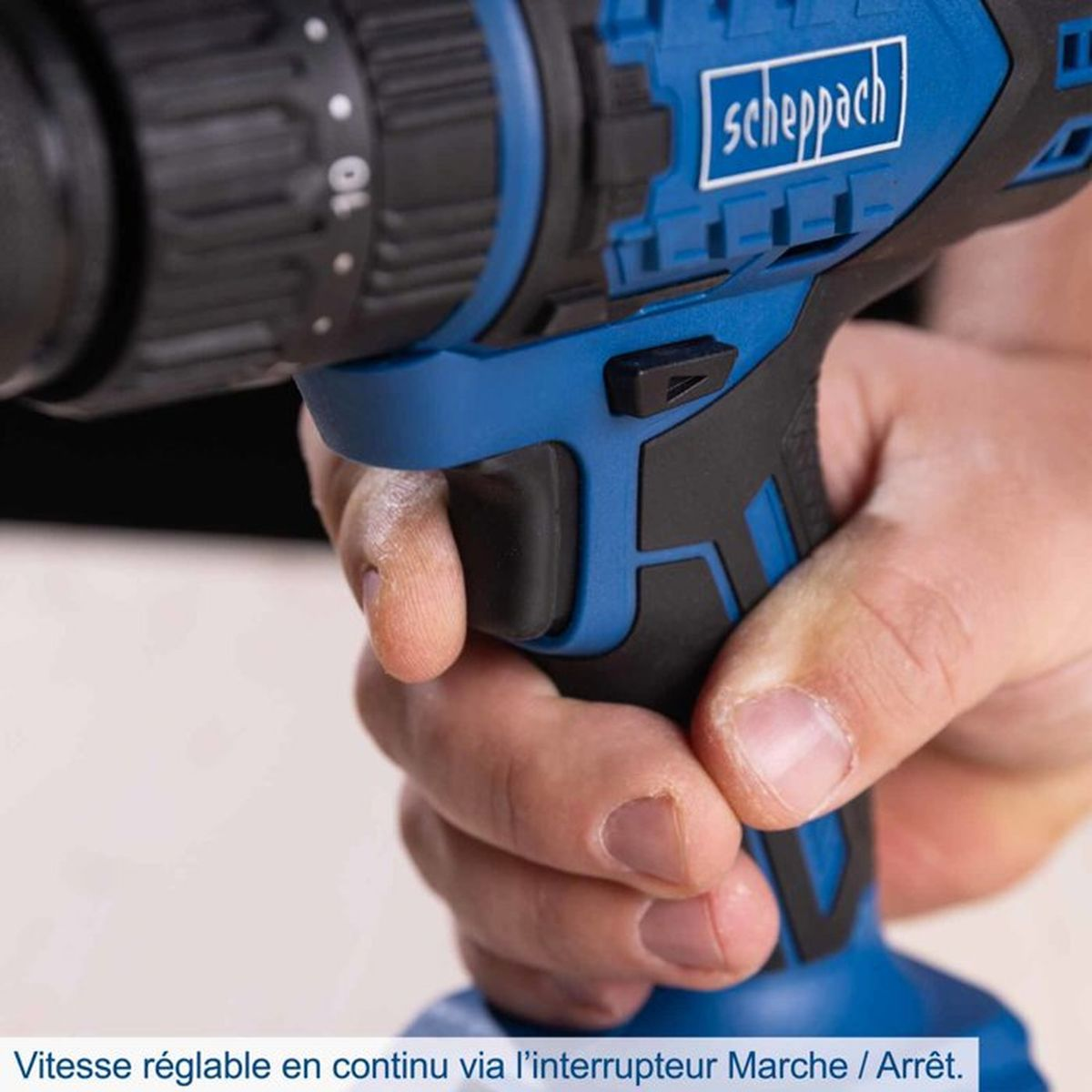 Hand hält eine blaue Scheppach Akkubohrmaschine am Griff.