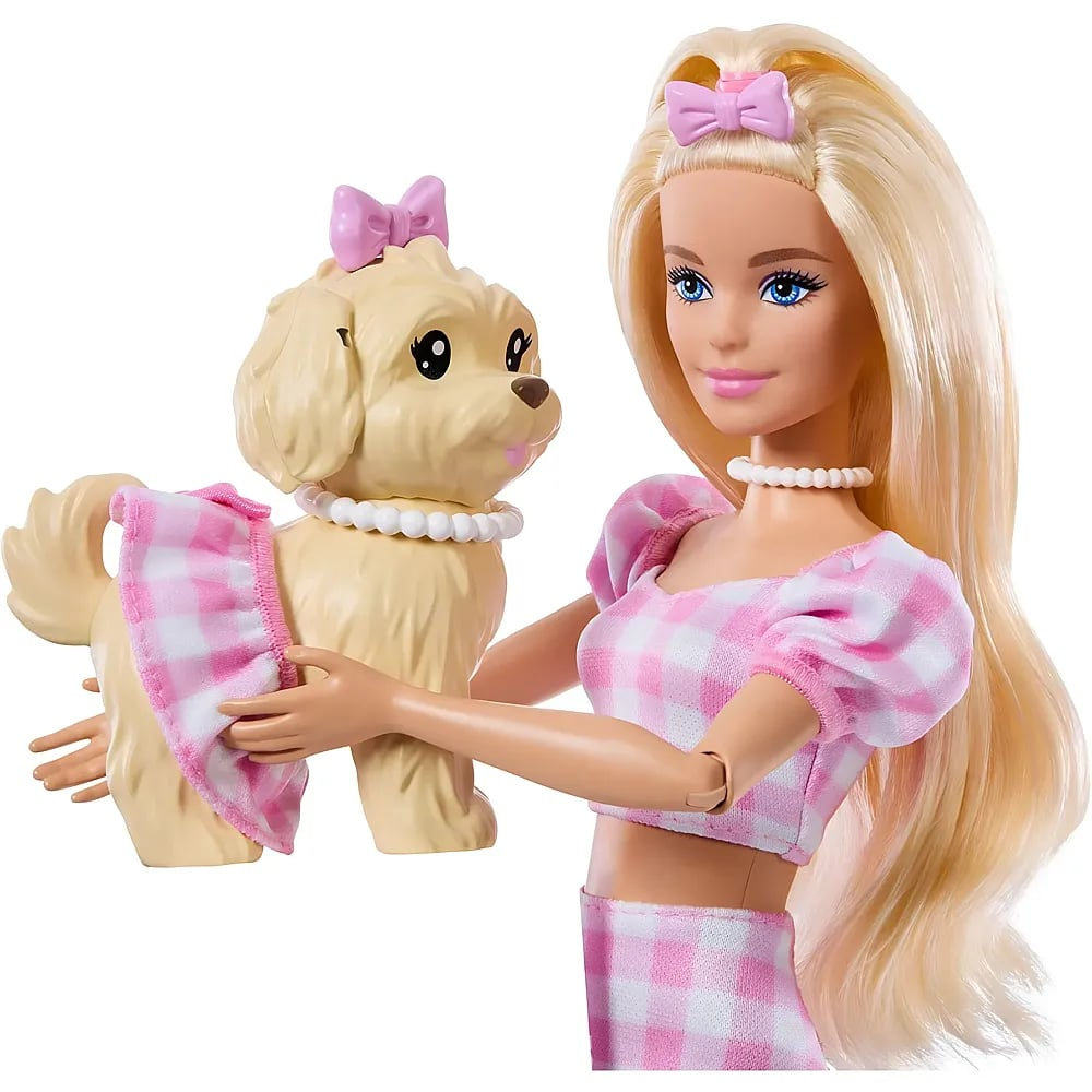 Una muñeca rubia con vestido de cuadros rosa sostiene a un perrito con collar de perlas.