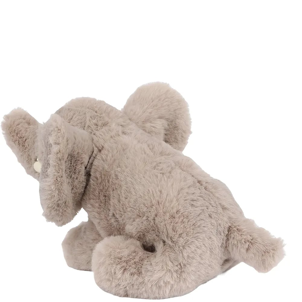 Ein kleiner, flauschiger Plüsch-Elefant in Grau sitzt auf einer weißen Oberfläche und blickt zur Seite.
