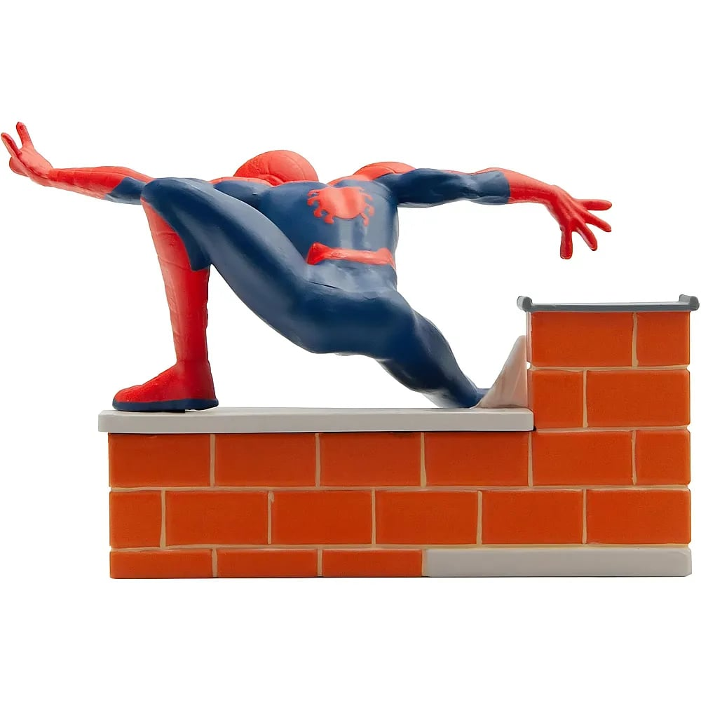 Una figura de acción de Spider-Man agachada sobre un muro de ladrillo naranja.
