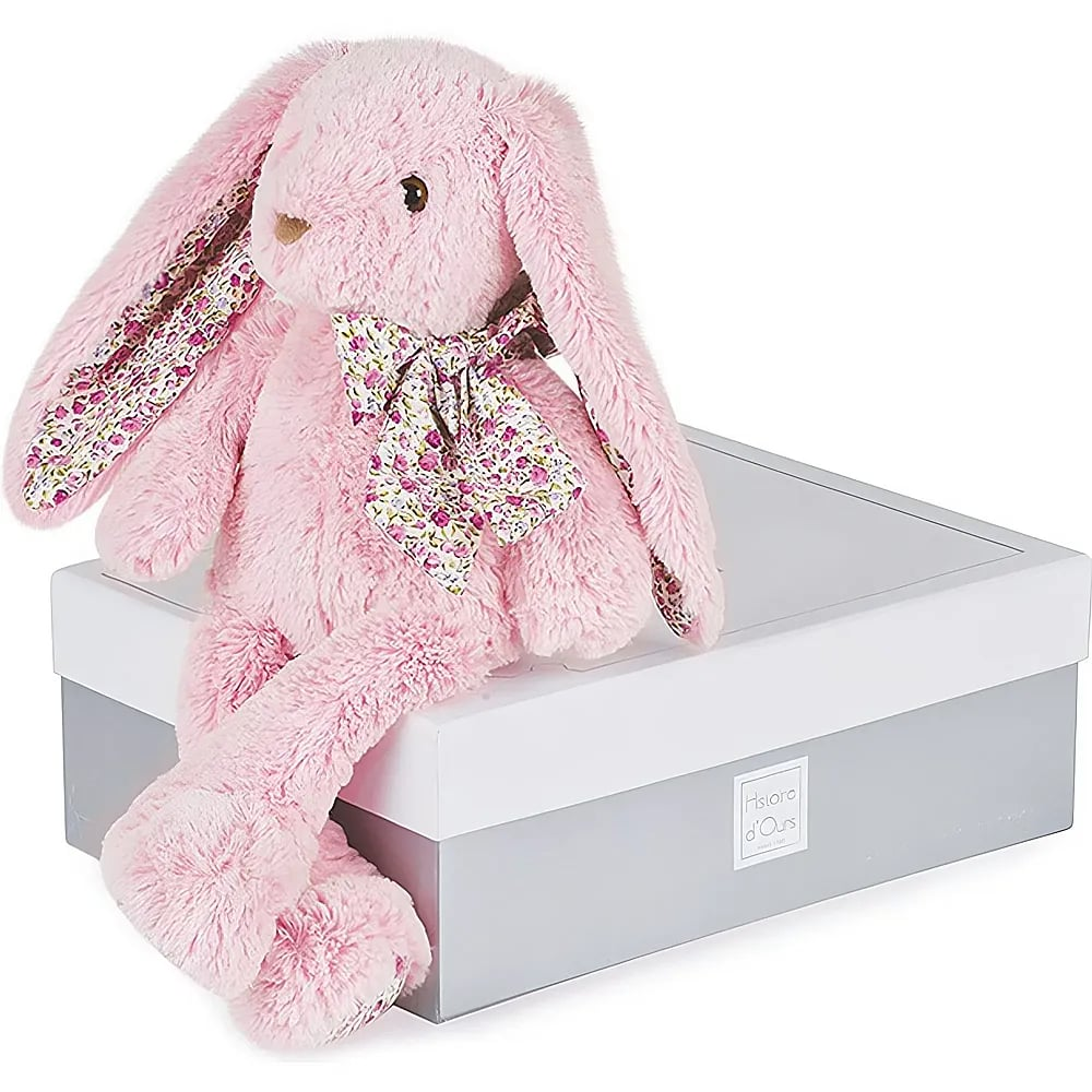 Ein flauschiger rosa Plüschhase sitzt auf einer weiß-grauen Geschenkschachtel mit Blumenschleife.