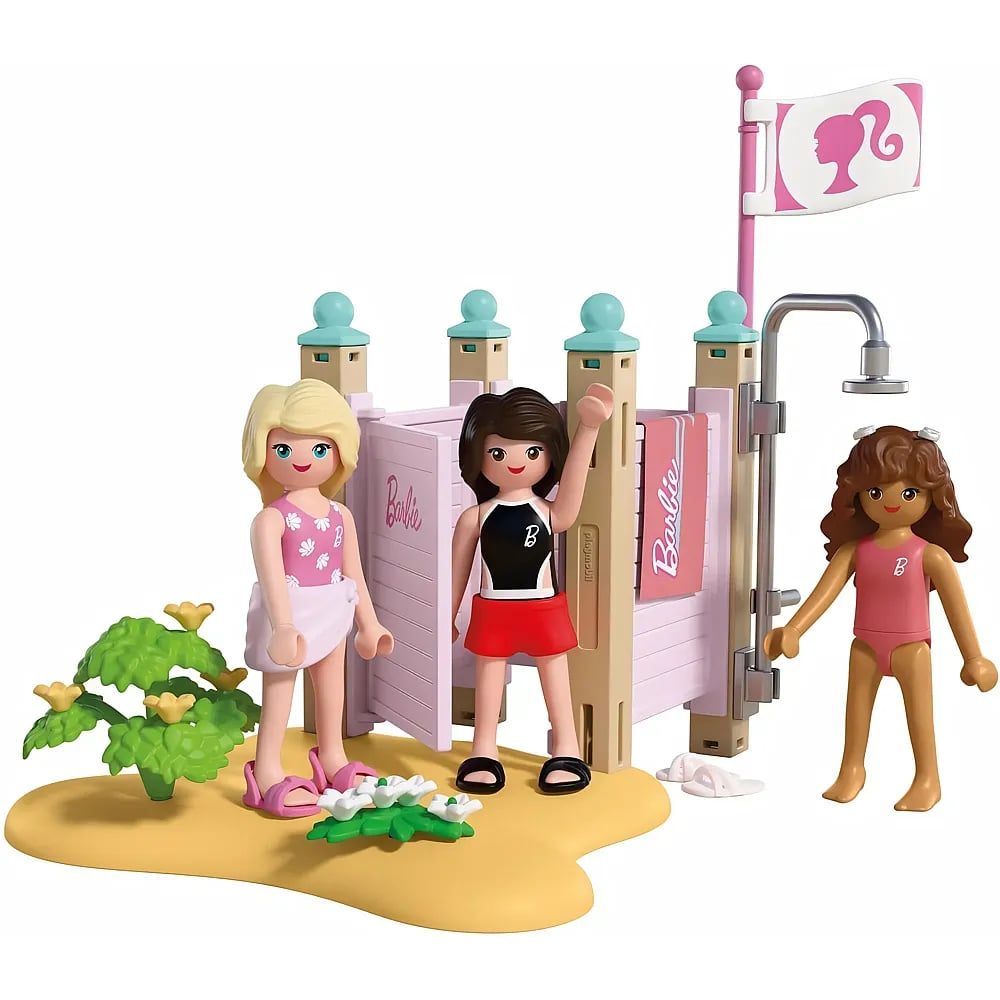 Tres figuras de Barbie están cerca de un juego de playa con ducha y bandera sobre arena amarilla.