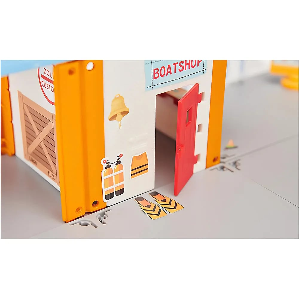 Ein Spielzeug-Bootshaus mit orangen Säulen, roter offener Tür, Tauchflaschen-Aufklebern und Flossen am Boden.