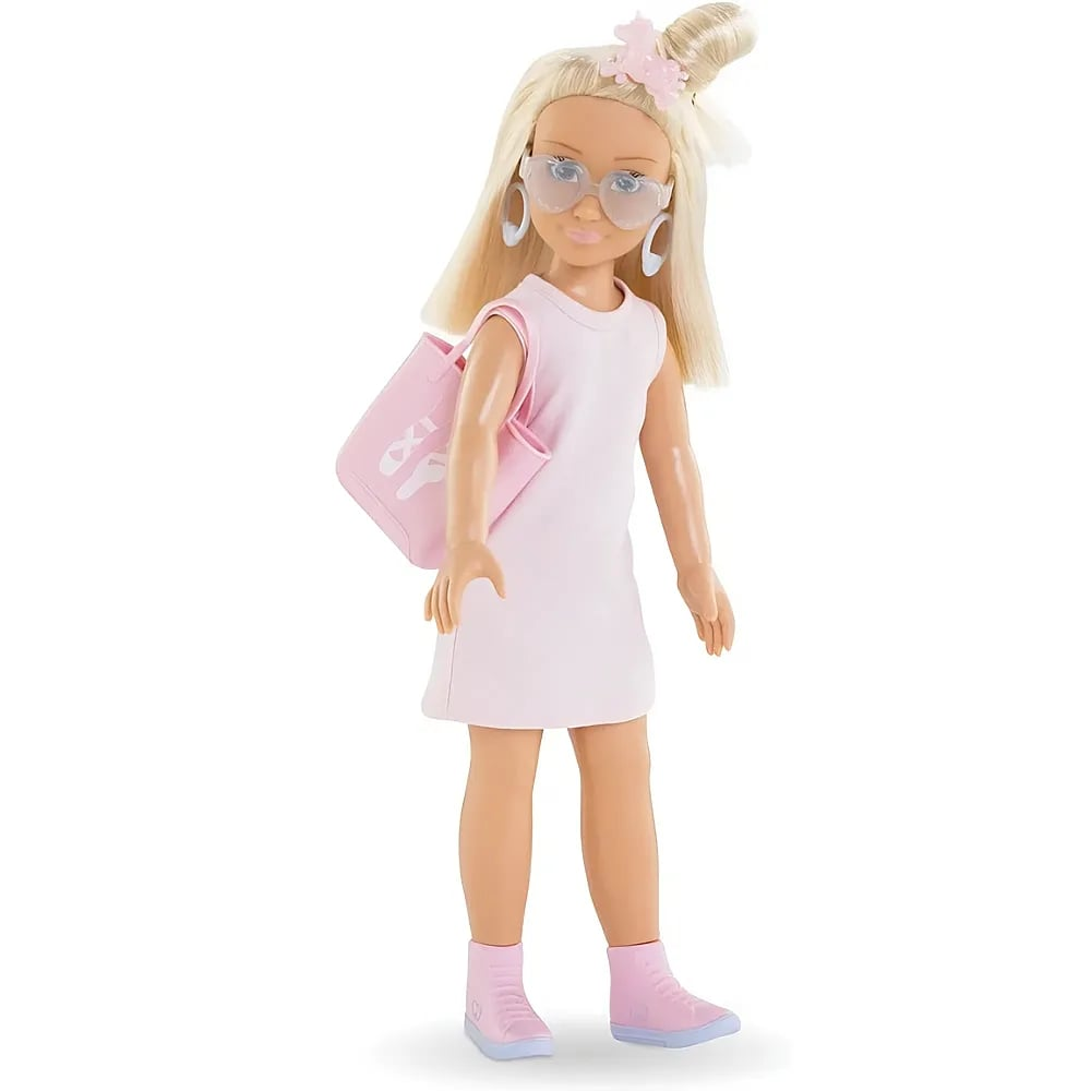 Eine blonde Modepuppe in Rosa mit Brille, Tasche und Turnschuhen steht auf weißem Grund.