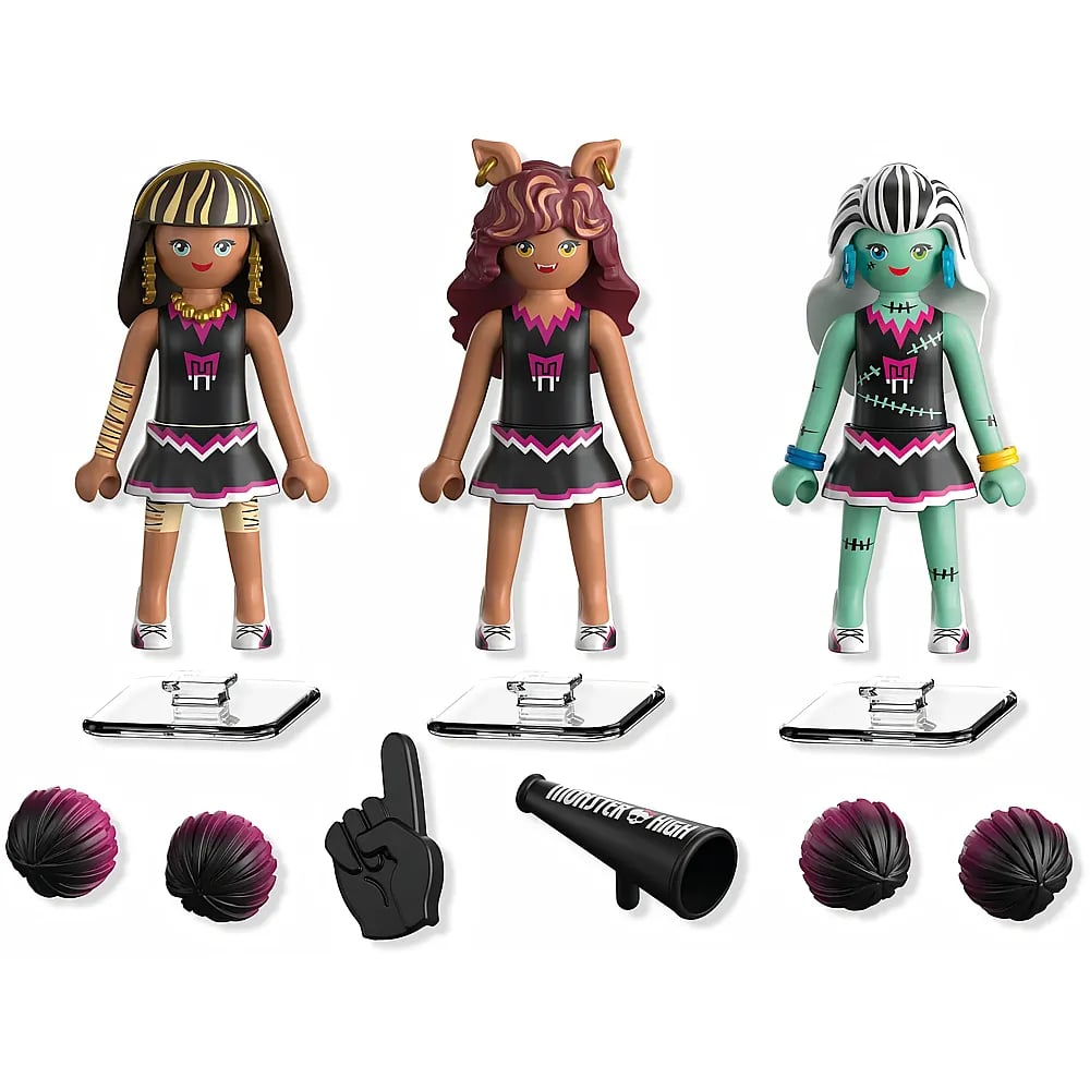 Tres muñecas Playmobil de Monster High con trajes de animadora negros, soportes y accesorios sobre fondo blanco.