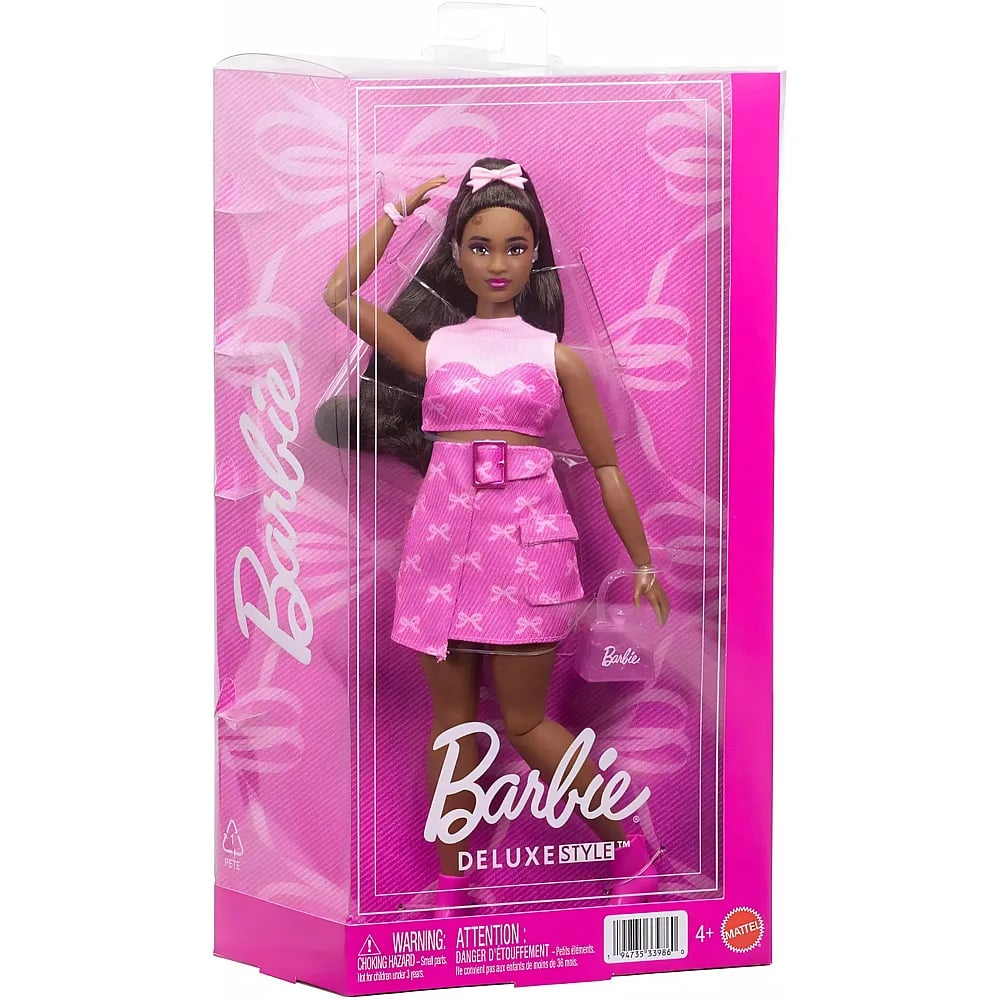Una muñeca Barbie Deluxe Style con cabello castaño en un conjunto rosa y bolso a juego, dentro de su empaque rosa.