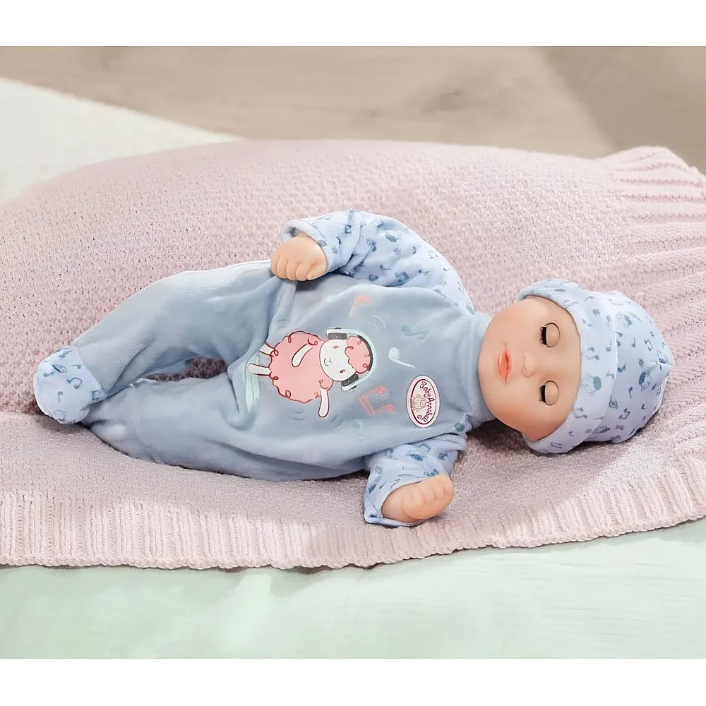 Eine Puppe in blauer Kleidung liegt auf einer rosa Decke.