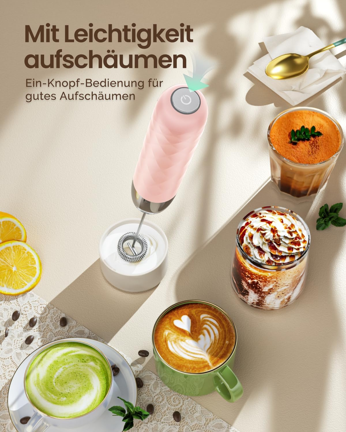 Ein rosafarbener Milchaufschäumer über Tassen mit Kaffee und Matcha auf einem Tisch.