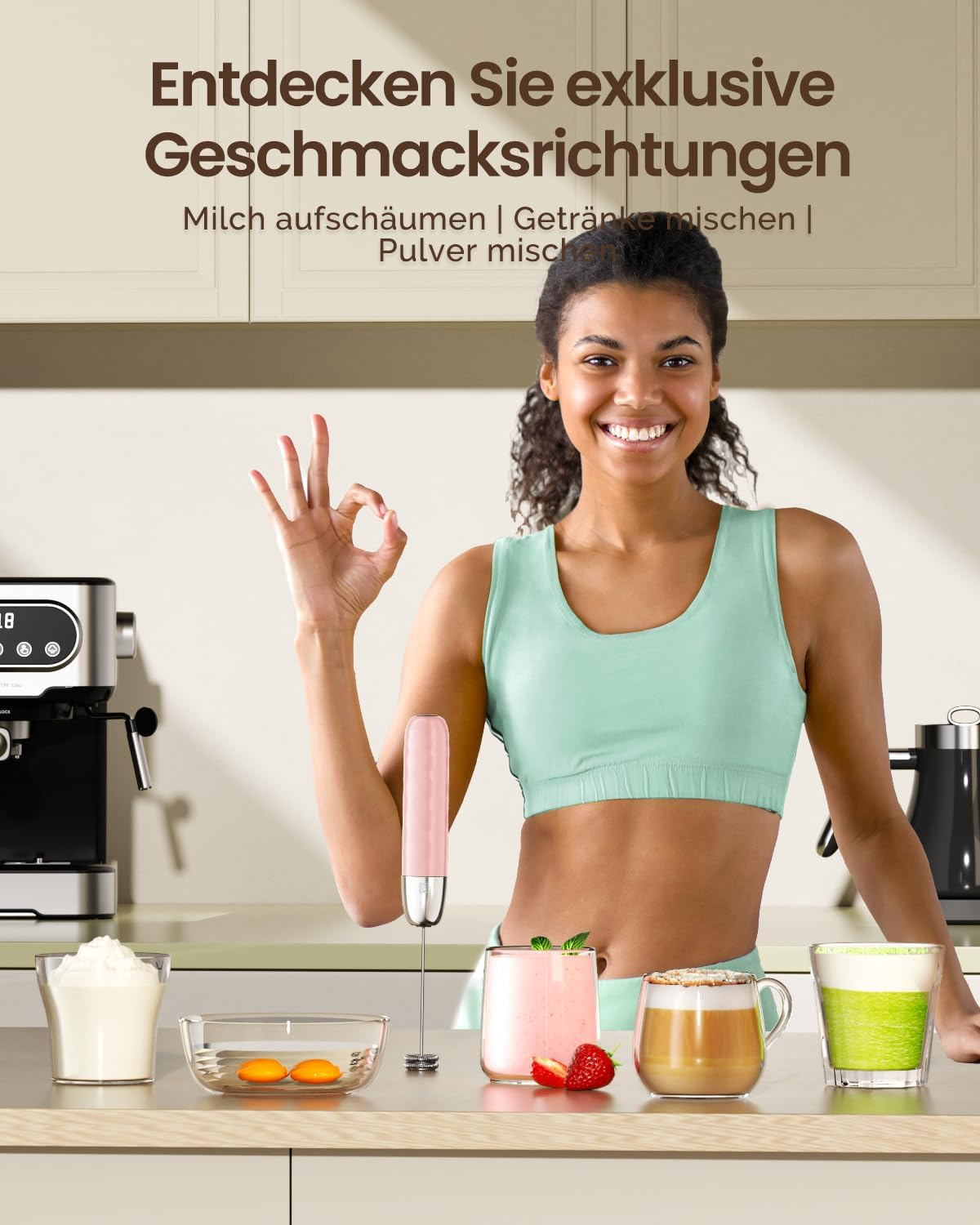Eine Frau in Sportkleidung lächelt und zeigt das OK-Zeichen, vor einer Küchentheke mit Milchaufschäumer und Gläsern.