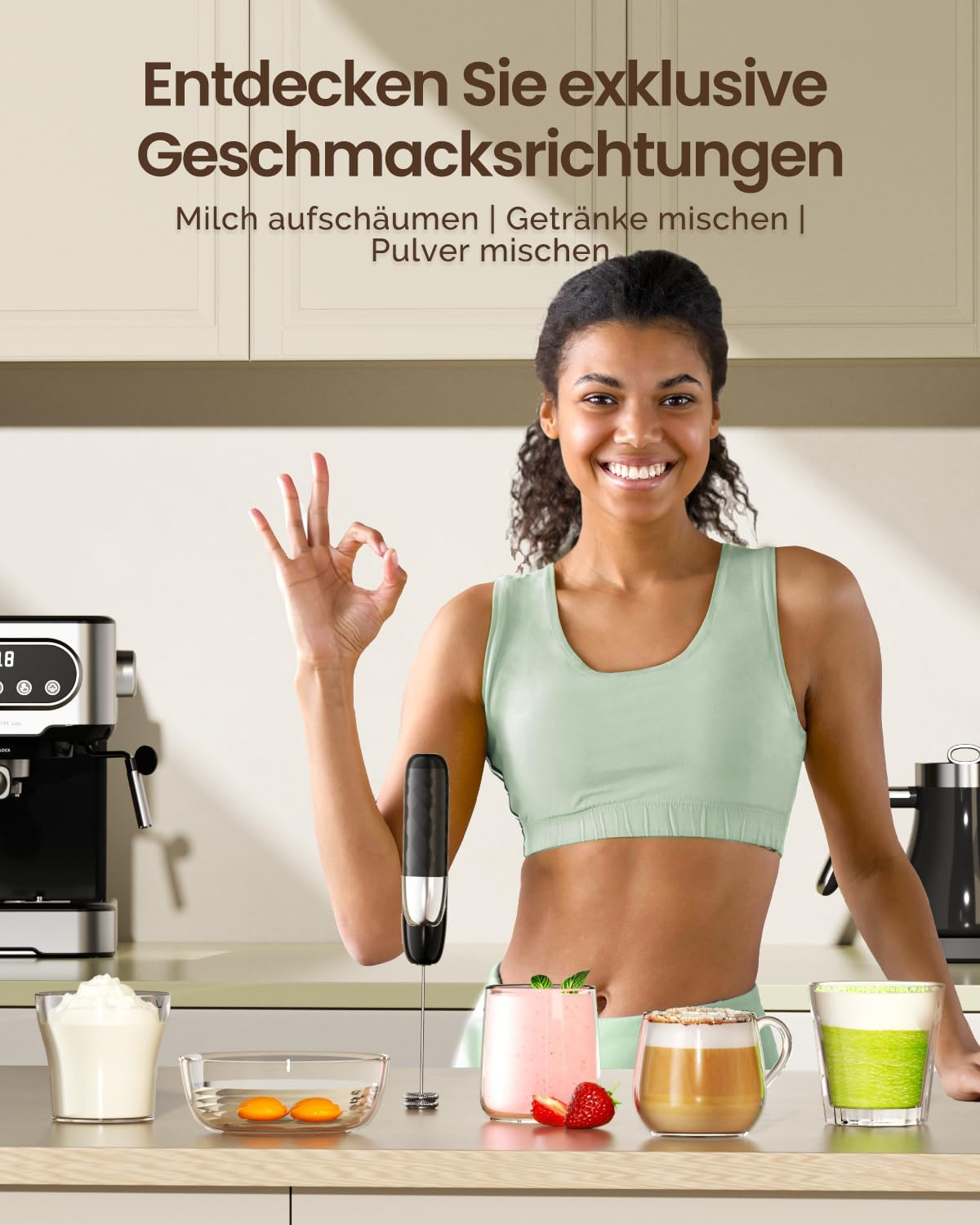 Lächelnte Frau macht ein OK-Zeichen neben einem Milchaufschäumer und Gläsern mit Getränken.