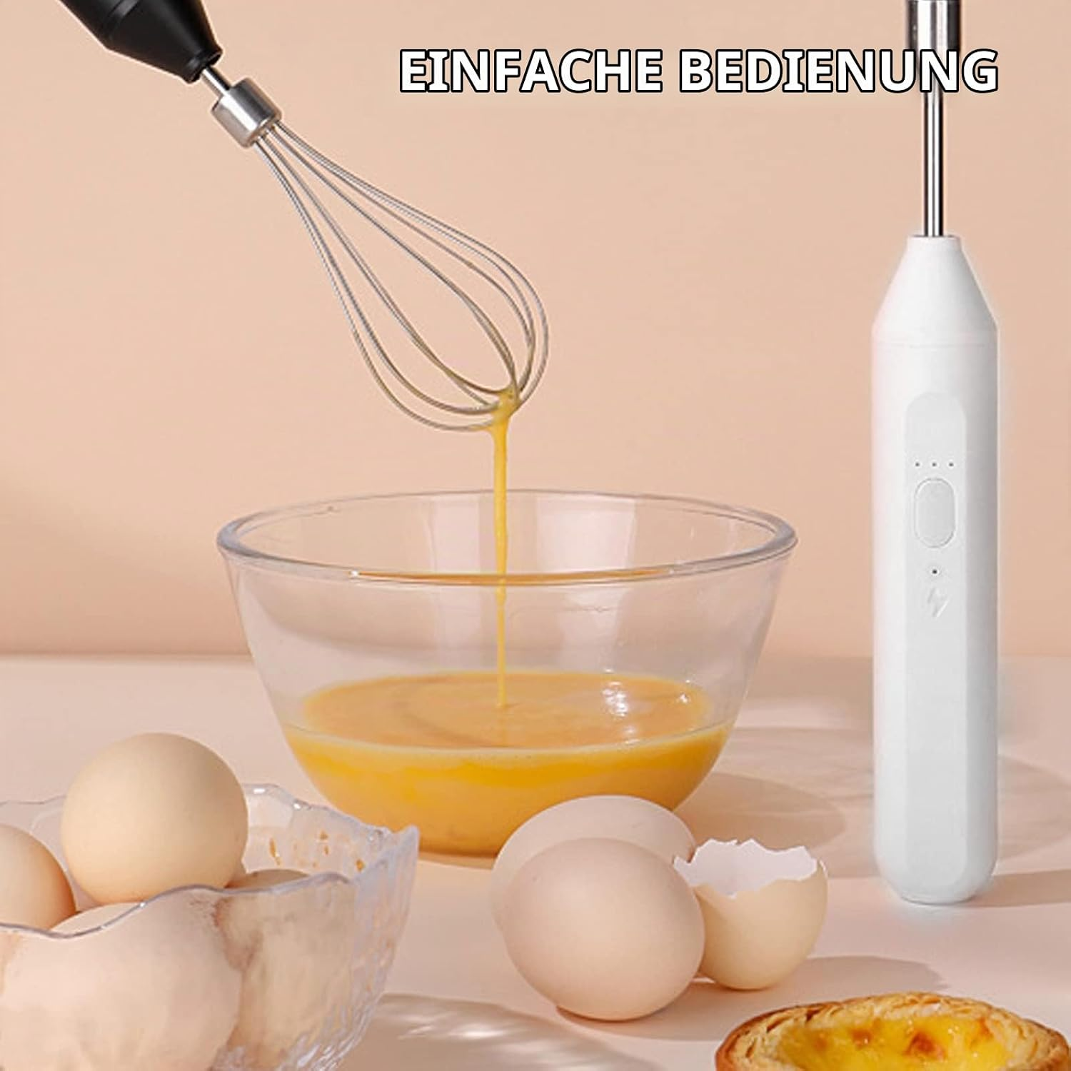 Ein Handrührgerät mischt Eier in einer Glasschüssel, umgeben von ganzen Eiern und einer Eierschale auf einem Tisch.