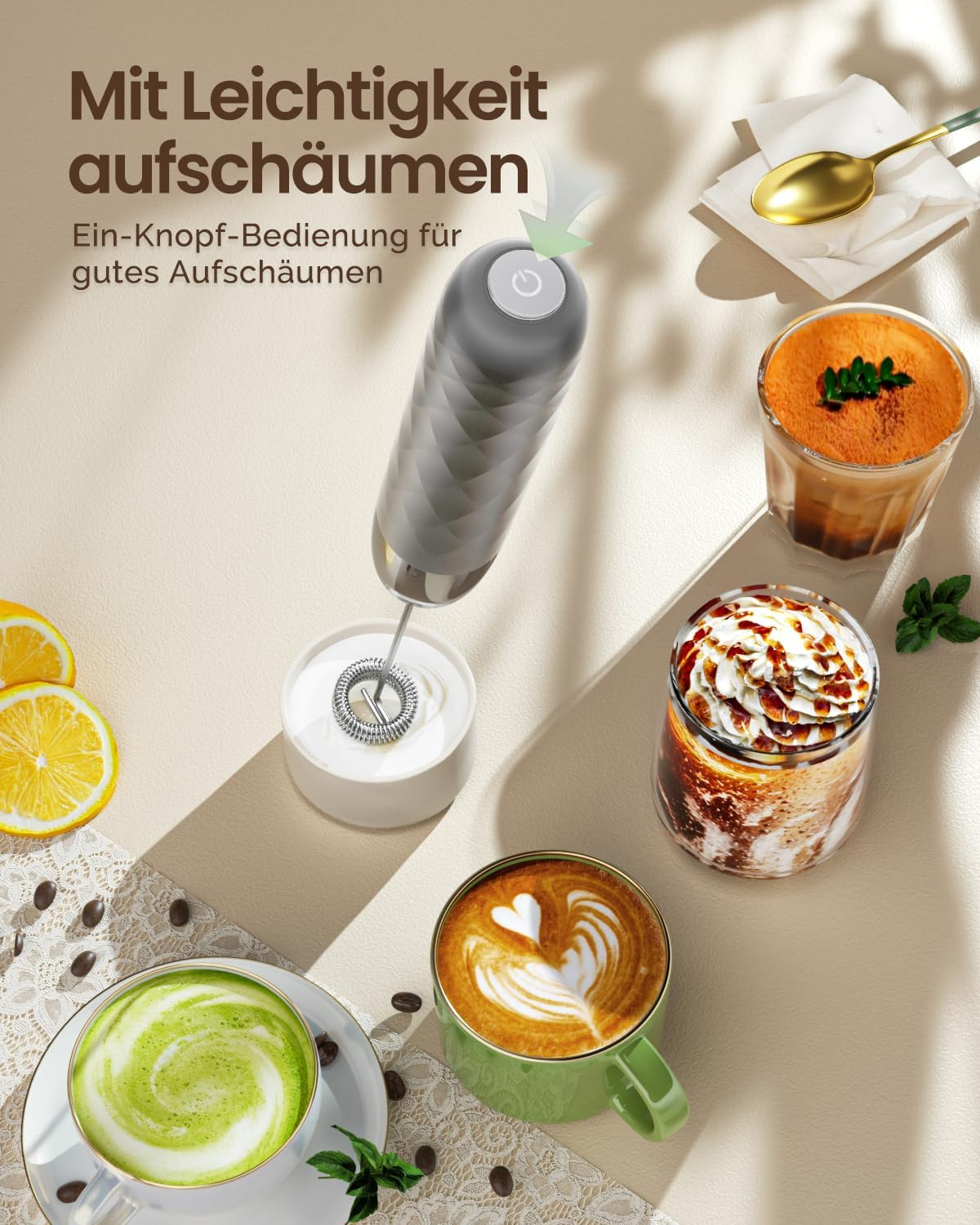 Ein grauer Milchaufschäumer frothiert Milch in einem kleinen Behälter neben verschiedenen Kaffeespezialitäten.