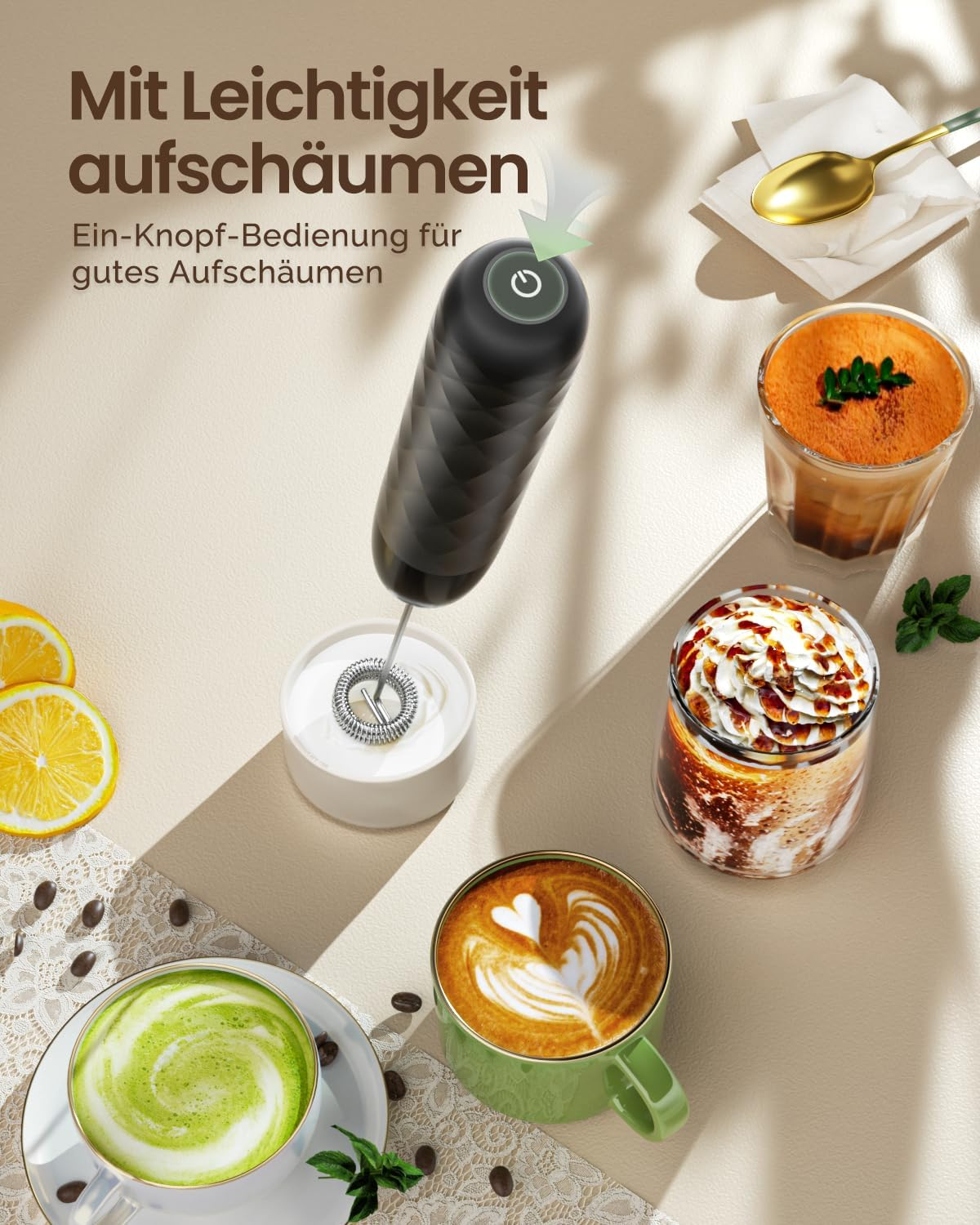 Ein schwarzer Milchaufschäumer steht neben Kaffeetassen, einer Tasse Matcha, Zitronenscheiben und einem goldenen Löffel.